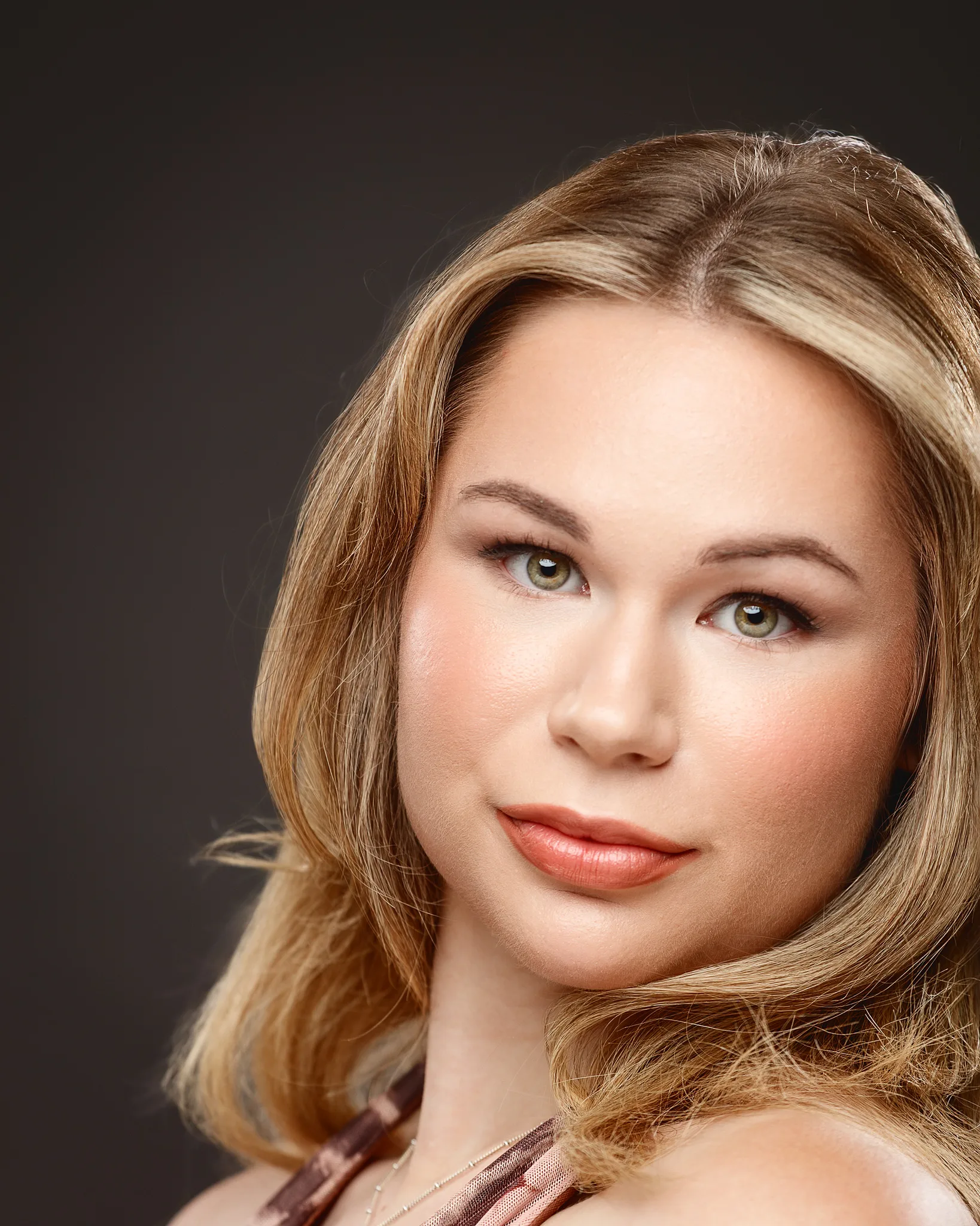 Professional headshot of woman with blonde hair against dark background