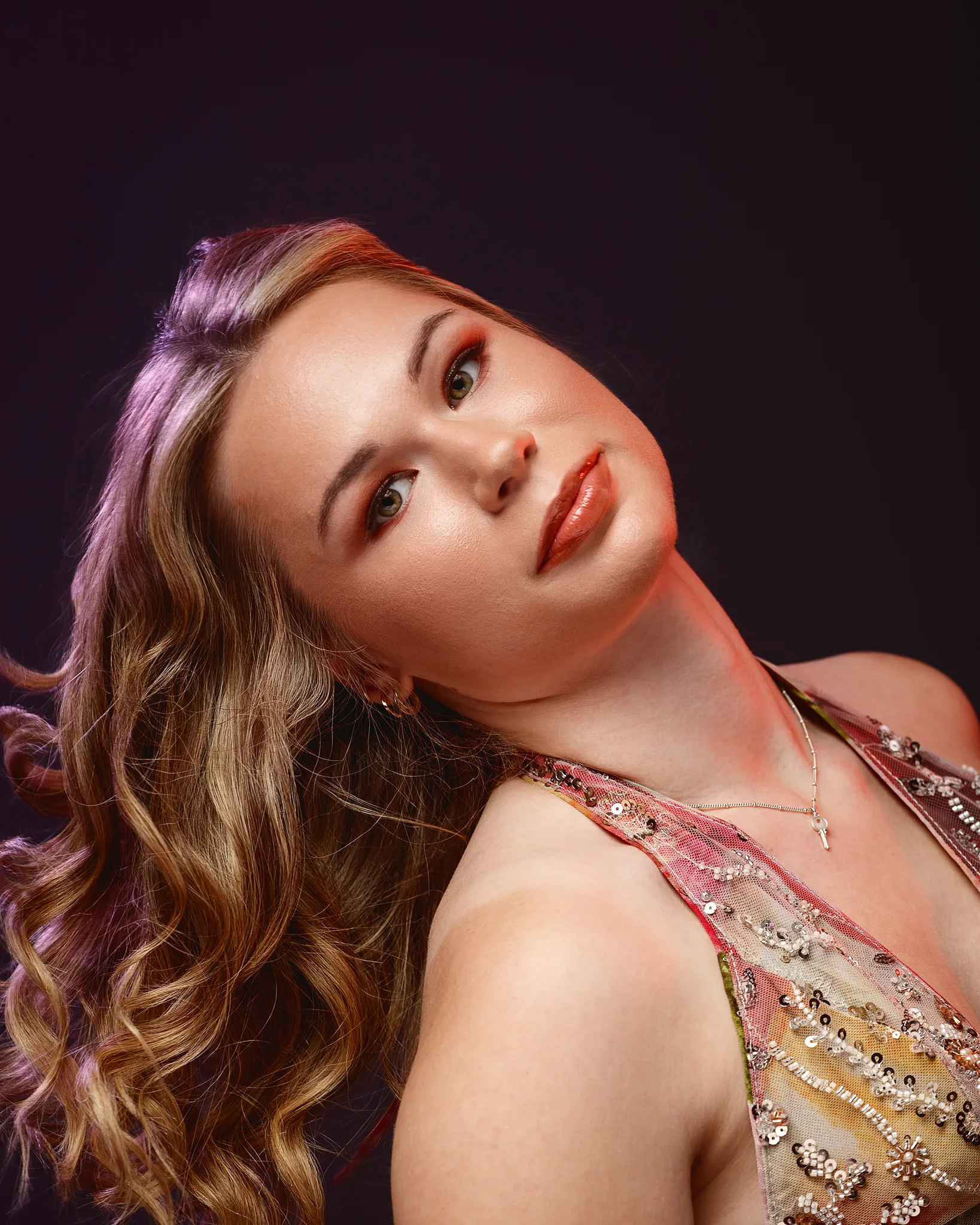 Woman with wavy hair and red makeup against dark background