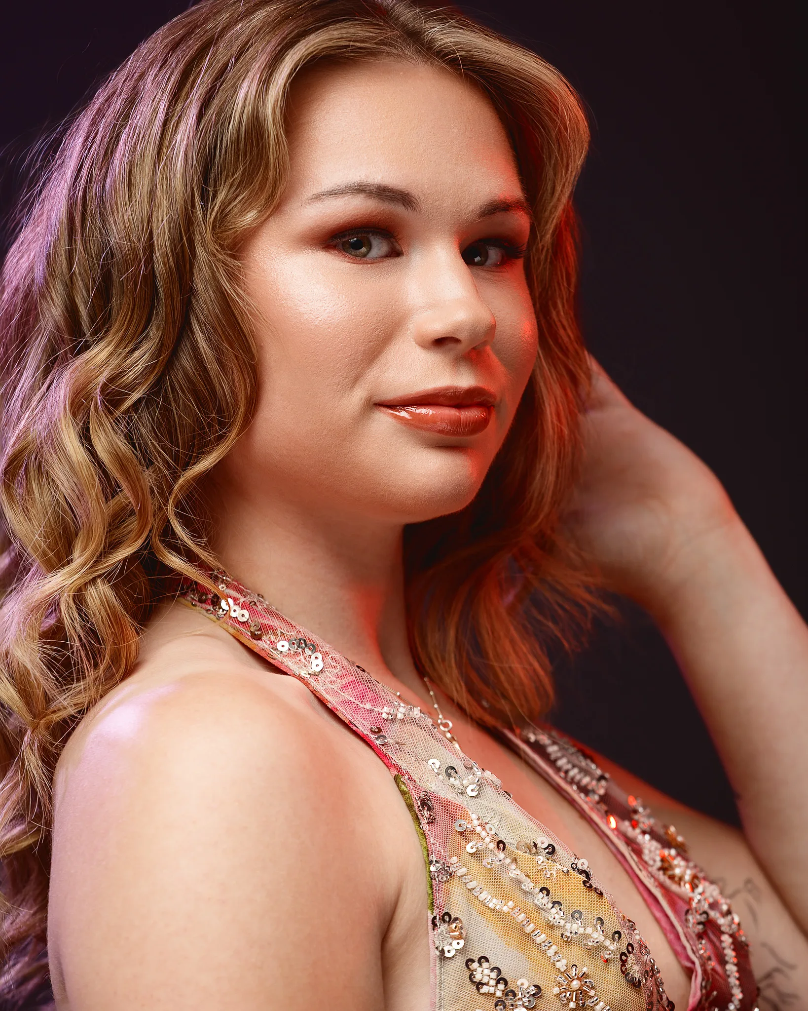Woman with wavy brown hair in red sequined dress