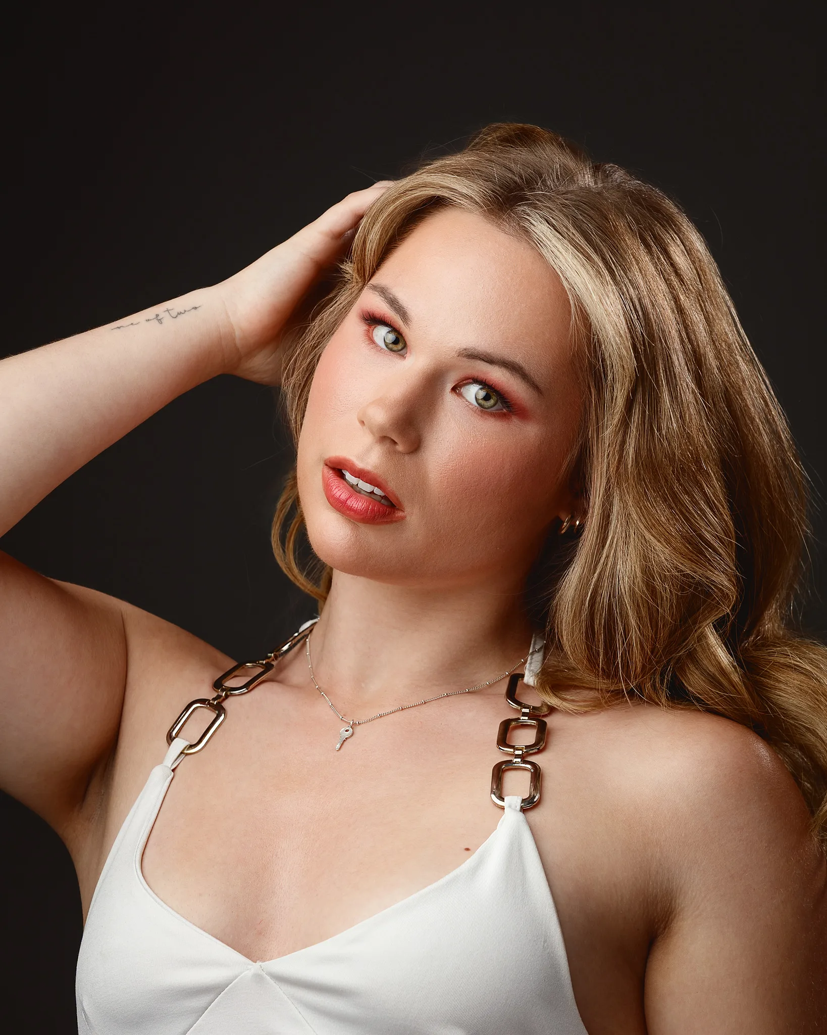 Woman with brown hair, red eyeshadow, wearing white top
