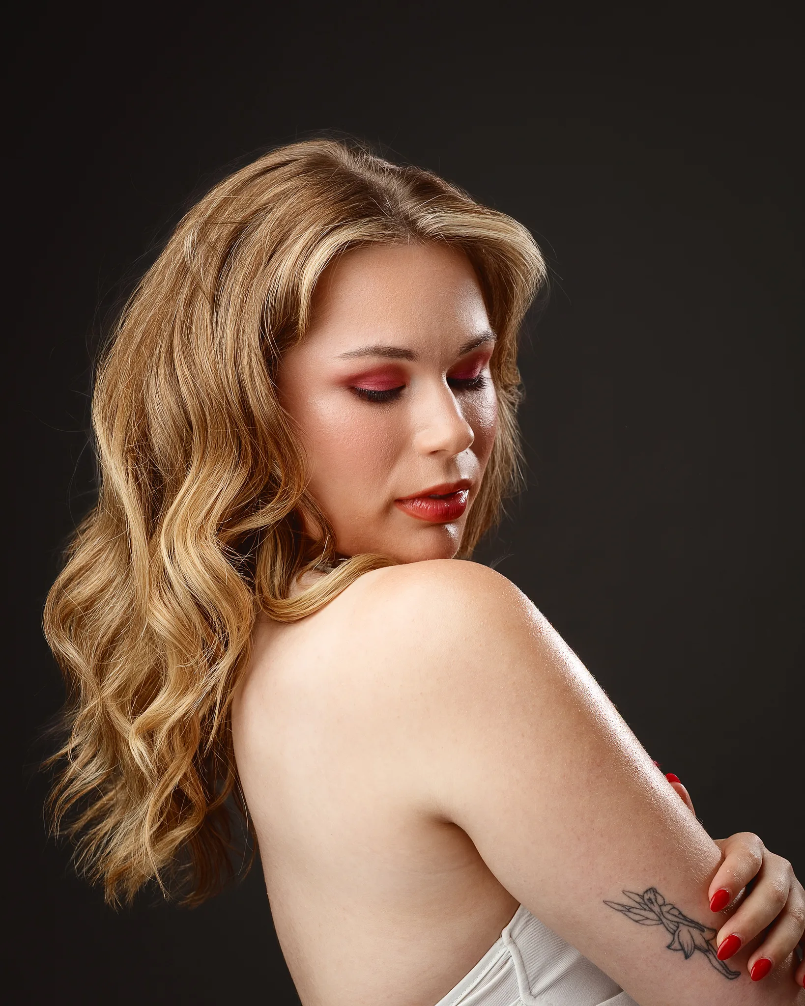 Woman with wavy blonde hair and red makeup, profile view