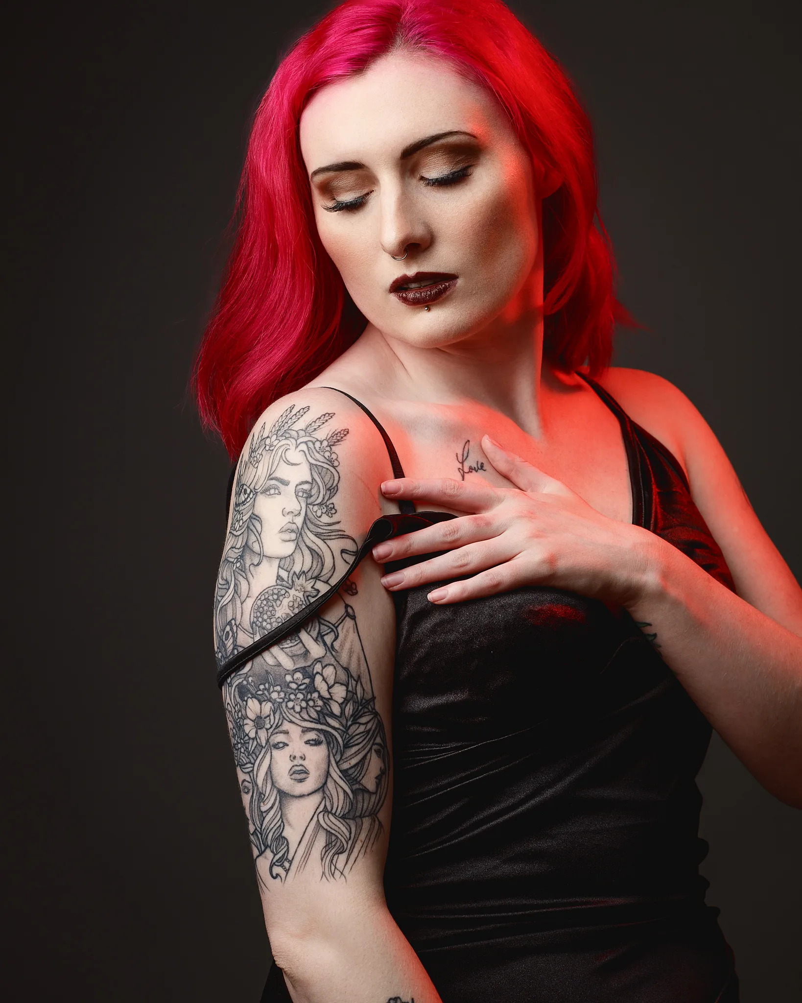 Woman with vibrant red hair displaying artistic arm tattoos