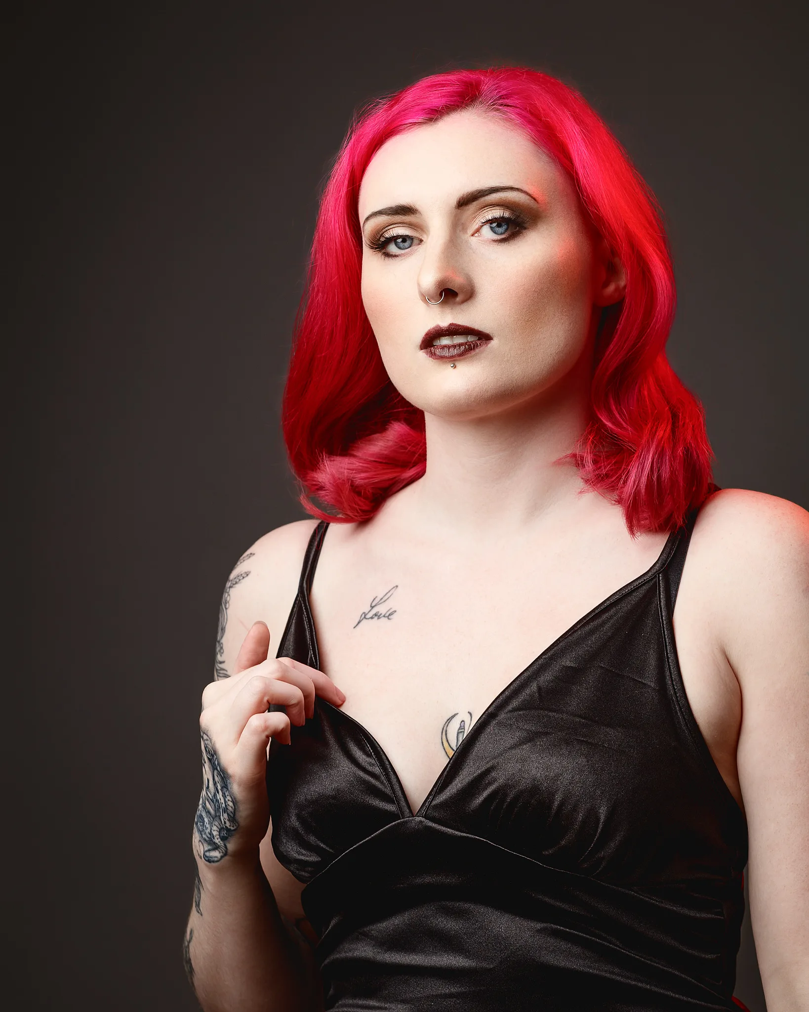 Woman with vibrant red hair and tattoos against dark background