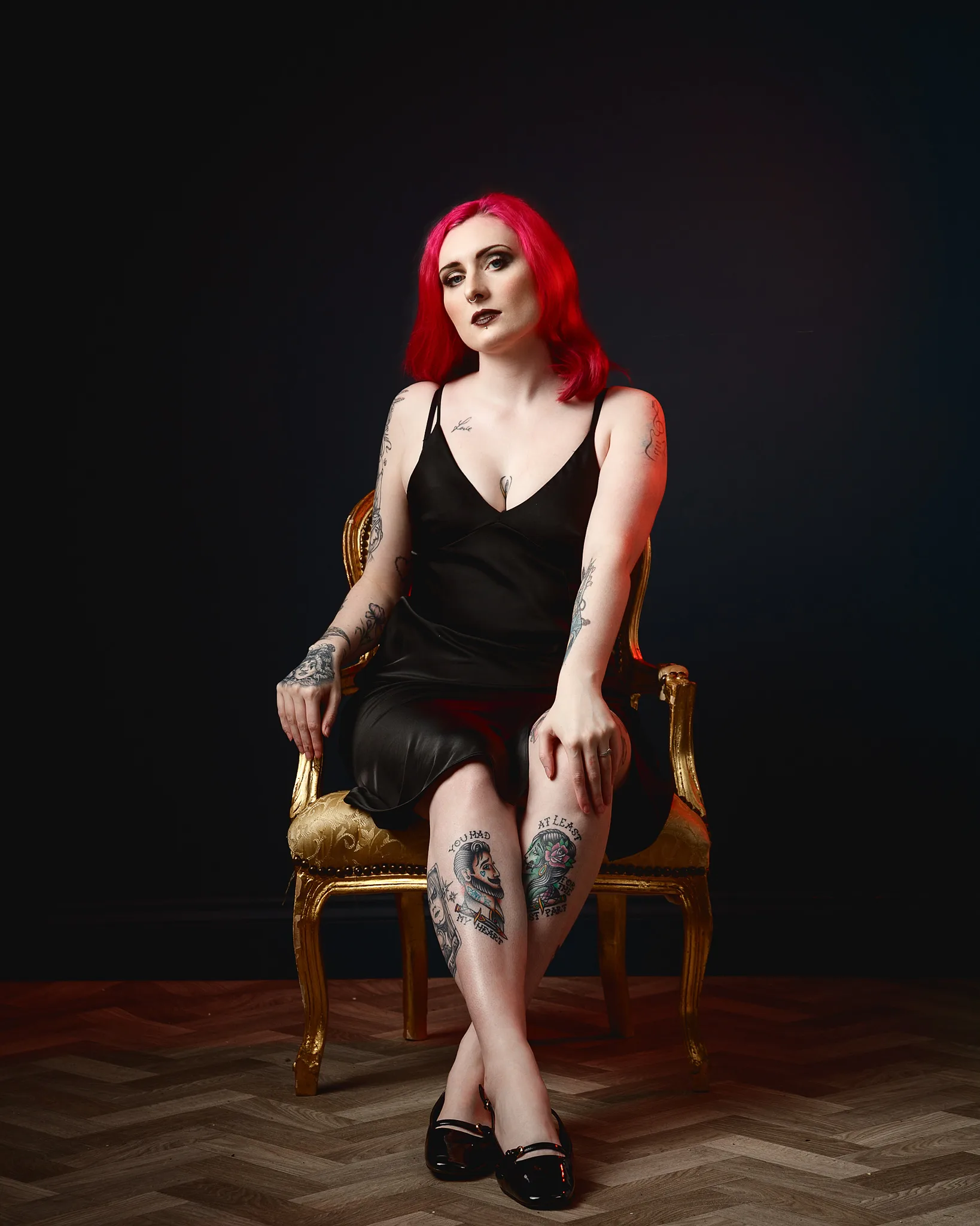 Woman with vibrant red hair sitting on ornate gold chair