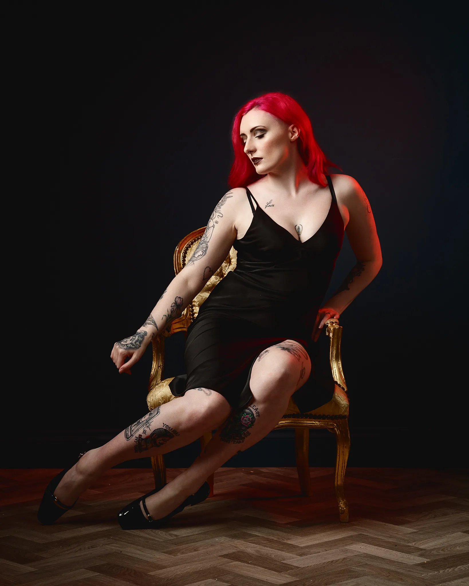 Woman with red hair and tattoos holding guitar on ornate chair