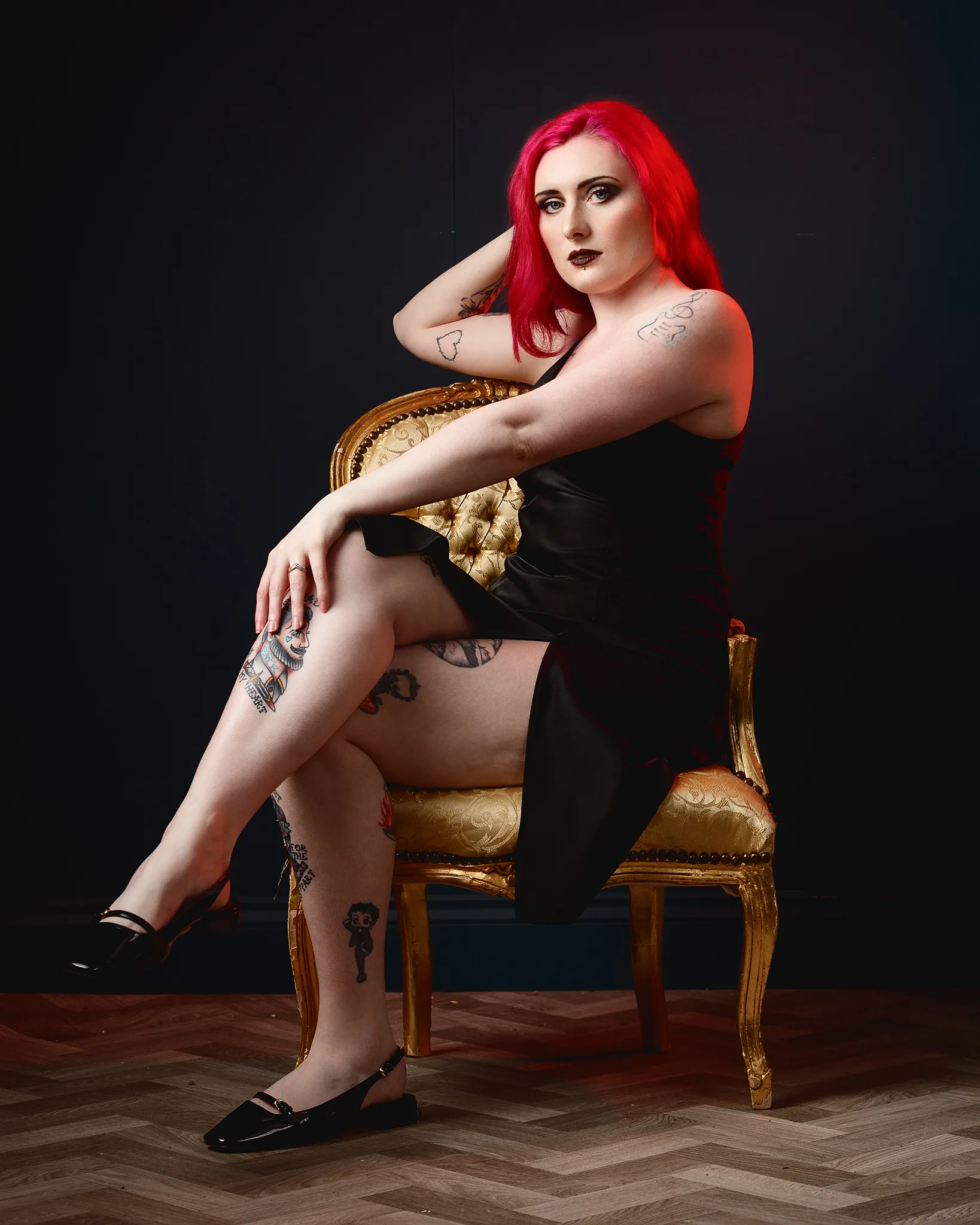 Woman with vibrant red hair seated on ornate golden chair
