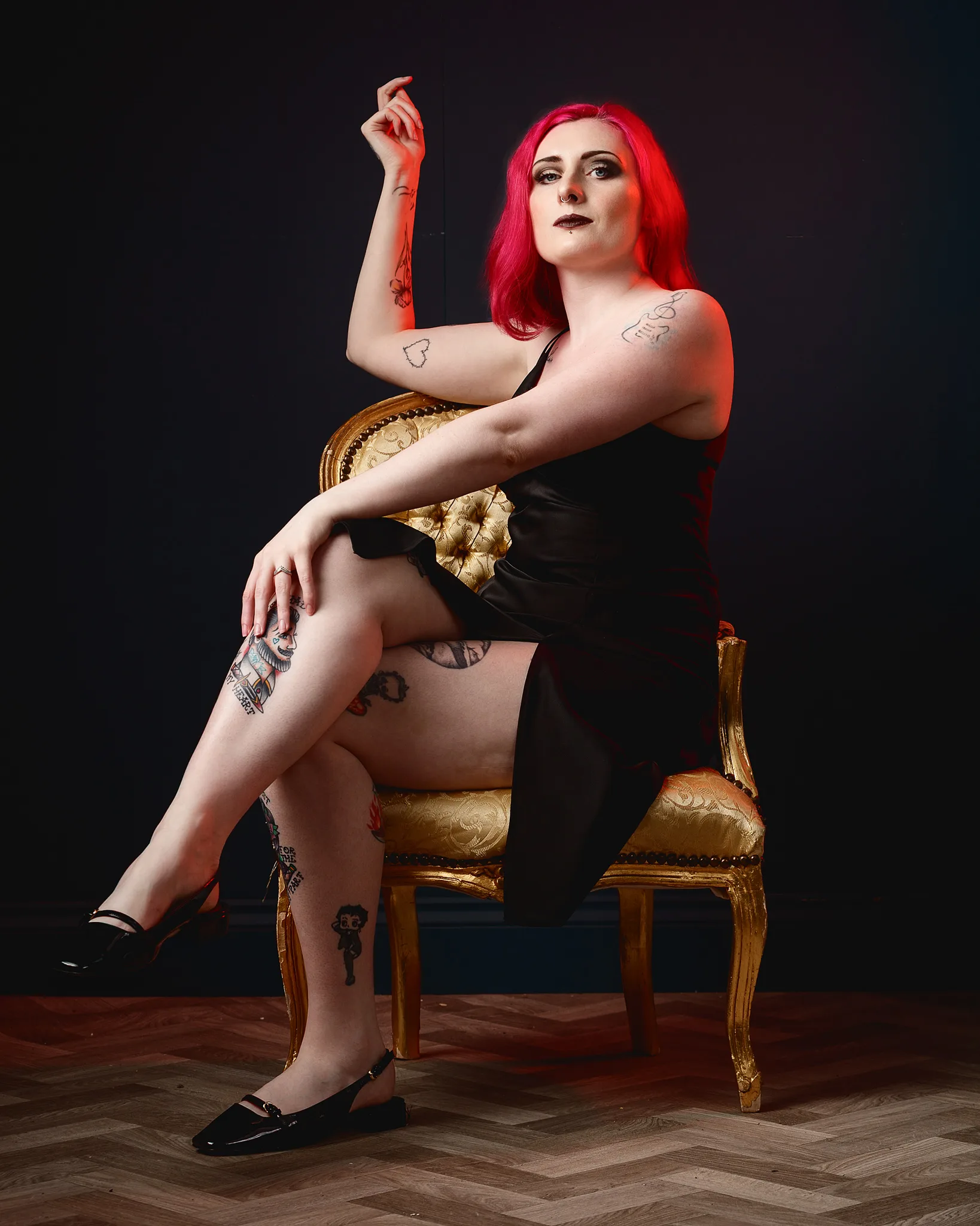 Woman with vibrant red hair sitting on ornate gold chair