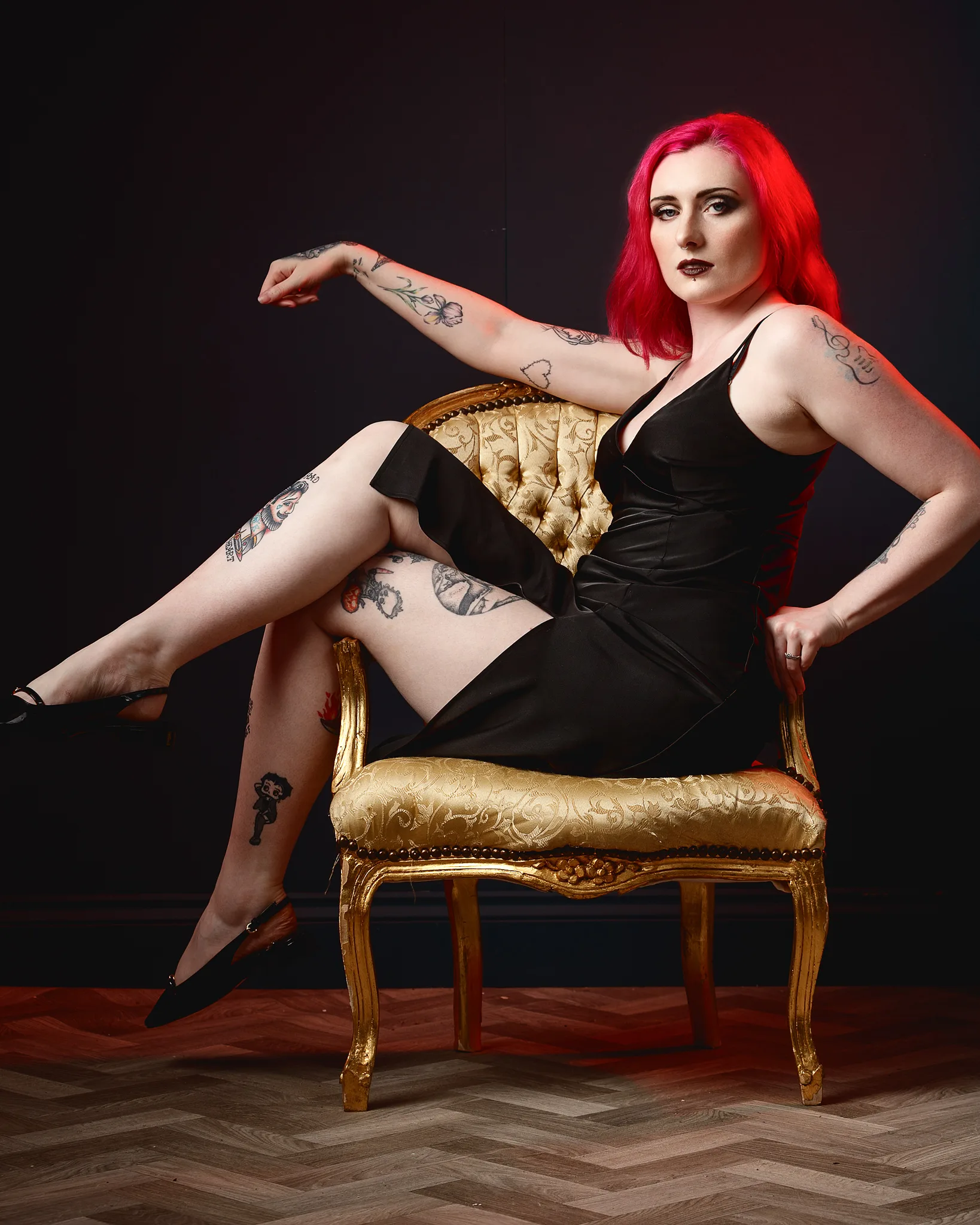 Woman with red hair and tattoos on ornate gold chair