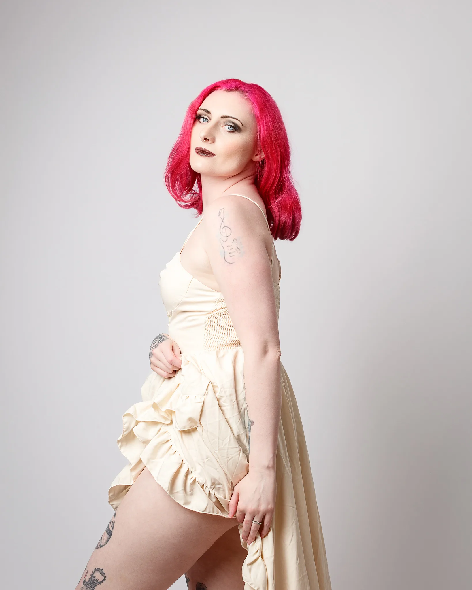 Woman with vibrant pink hair wearing cream coloured dress