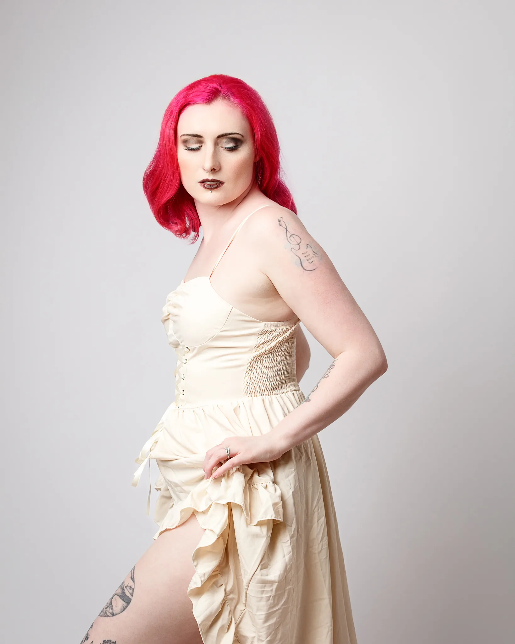 Woman with bright pink hair wearing cream corset dress