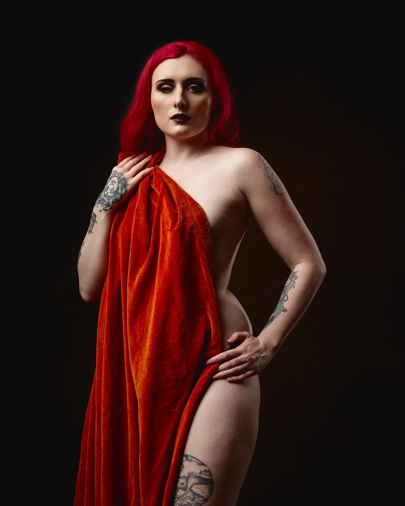 Woman with vibrant red hair wearing crimson draped fabric