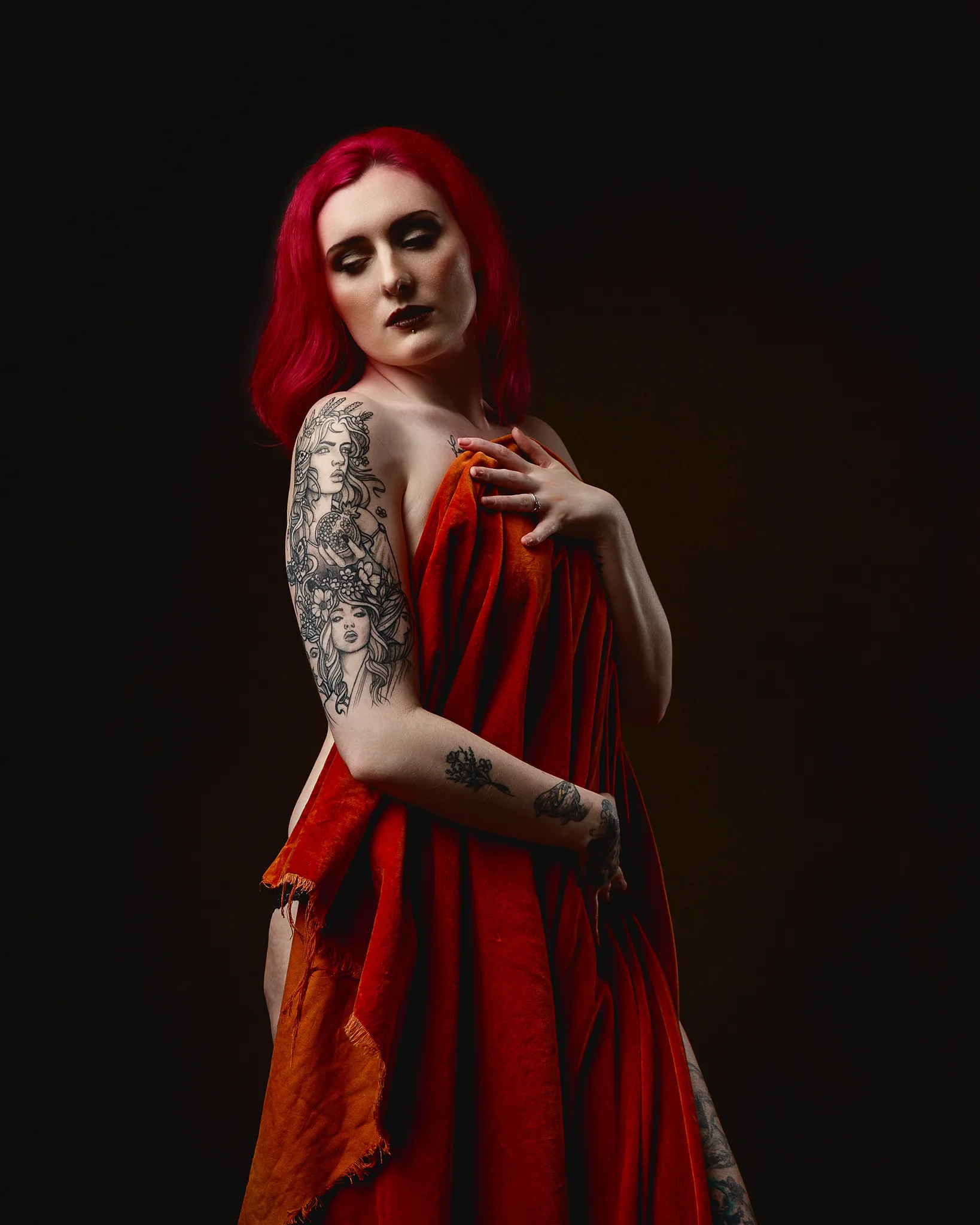 Woman with vibrant red hair and tattoos wearing red fabric