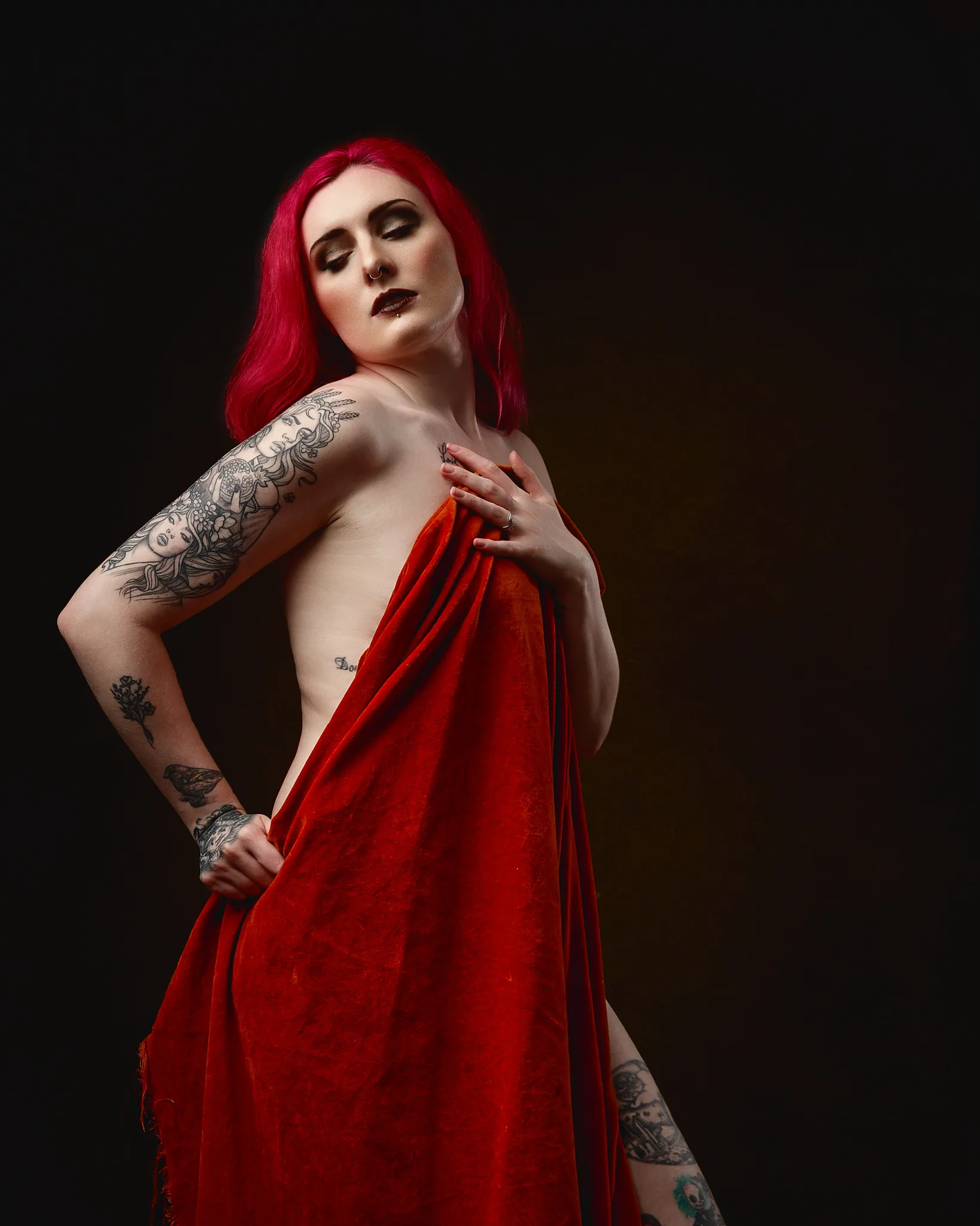 Woman with vibrant red hair and tattoos wearing red fabric