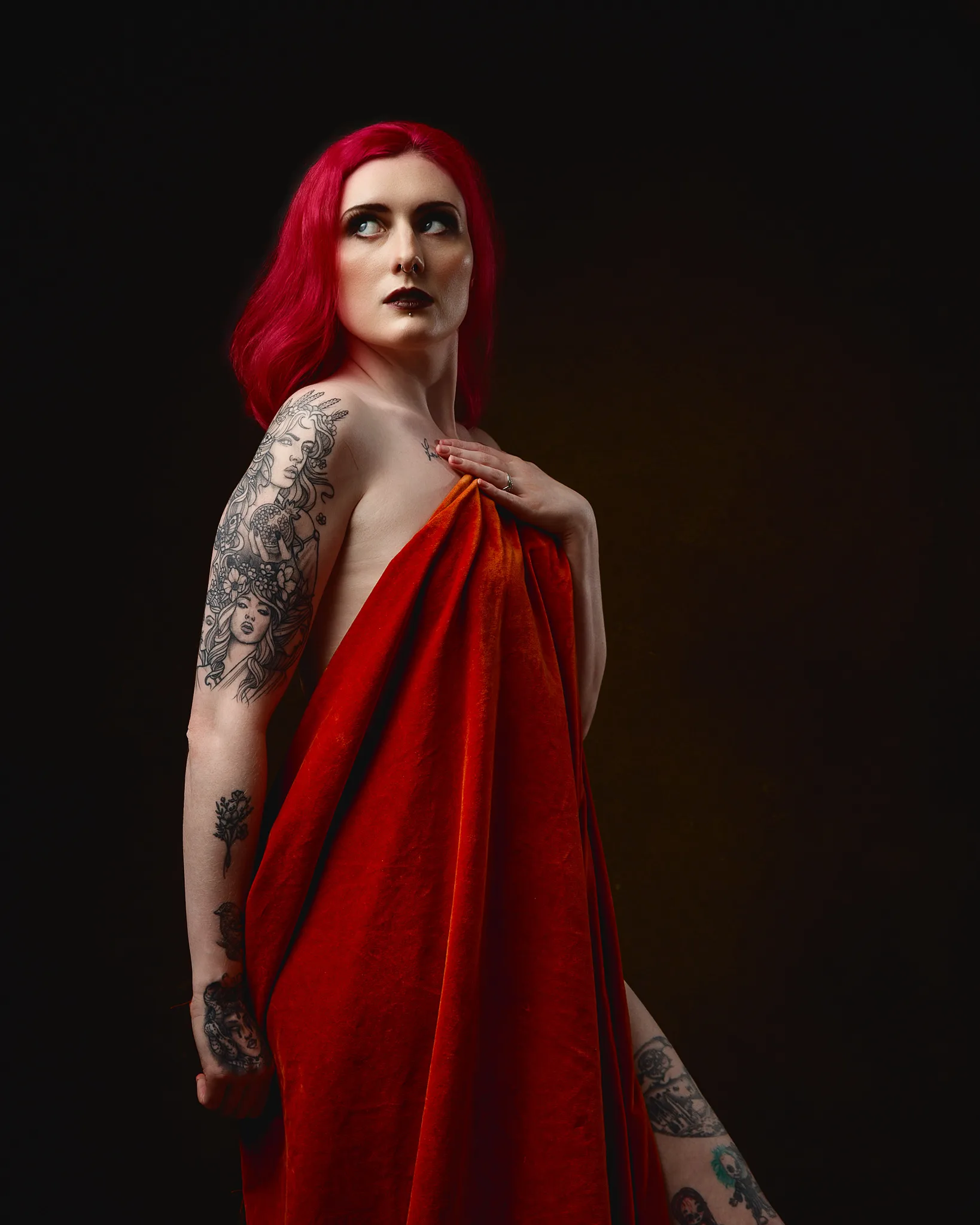 Woman with vibrant red hair and tattoos wearing red fabric