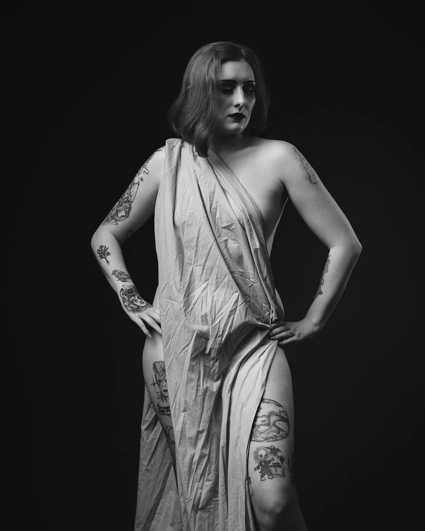 Black and white portrait of tattooed woman in draped fabric