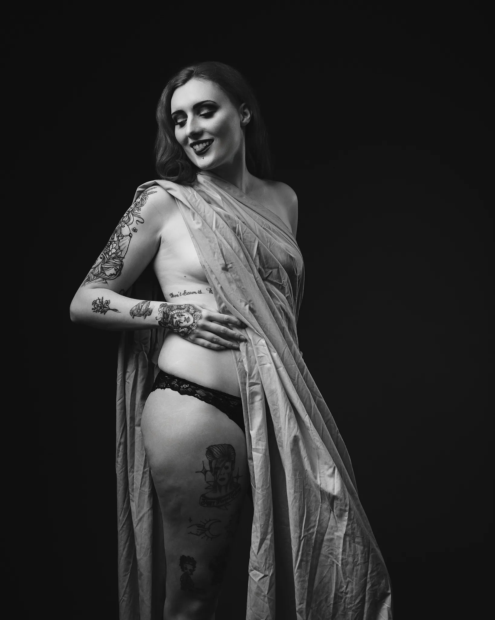 Black and white portrait of tattooed woman with sheer fabric drape