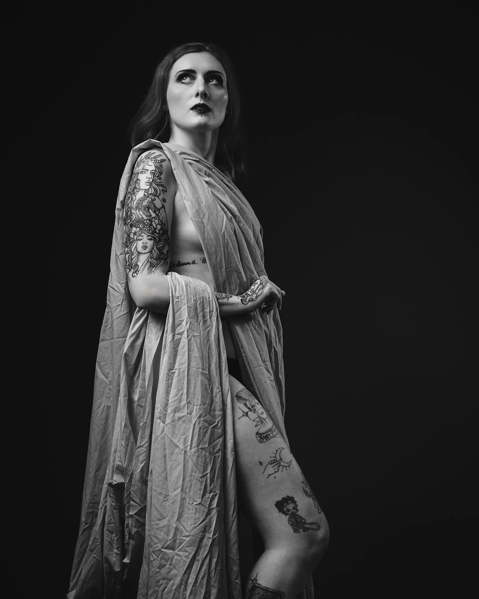 Woman with multiple tattoos in dramatic black and white portrait