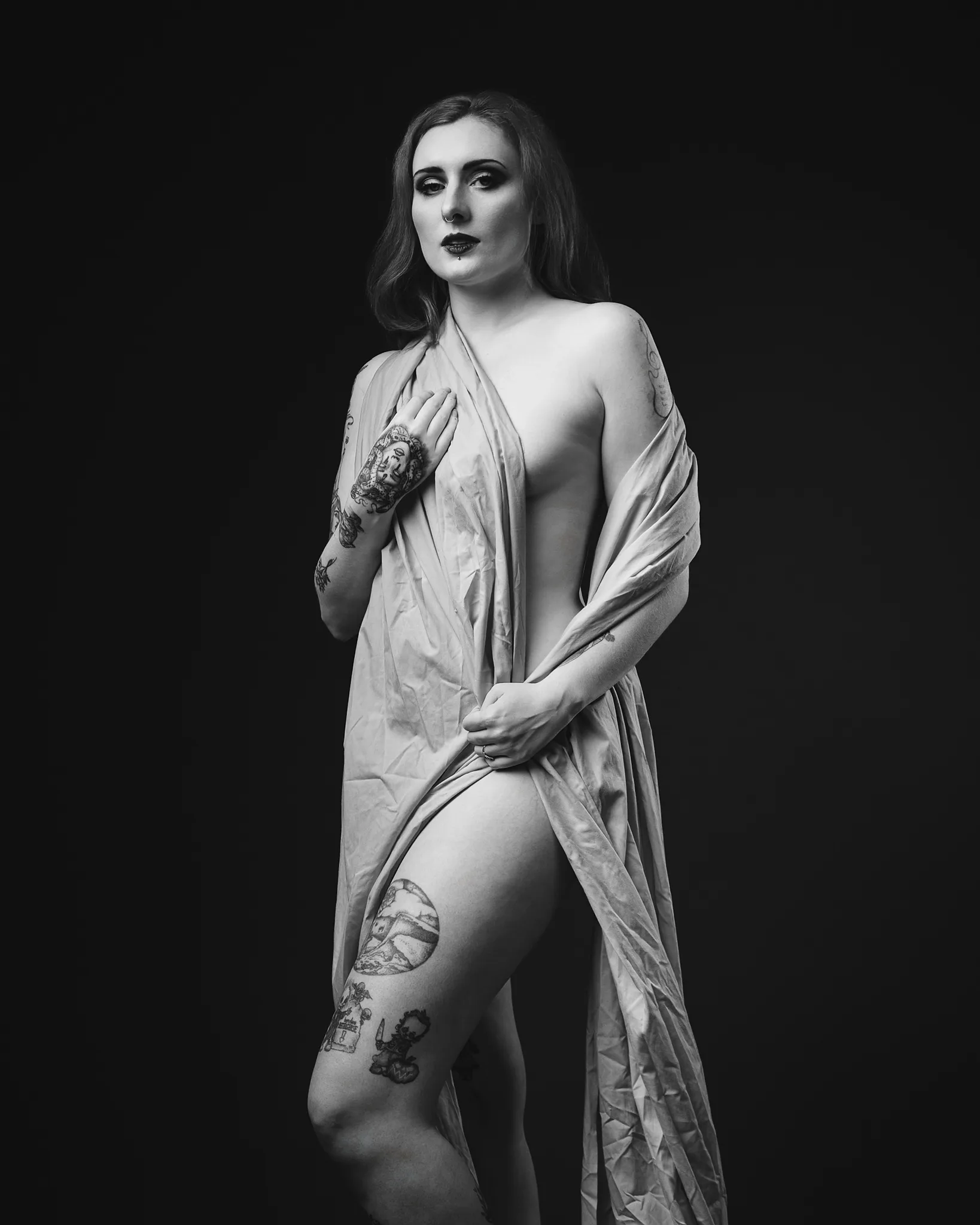 Black and white portrait of tattooed woman with draped fabric