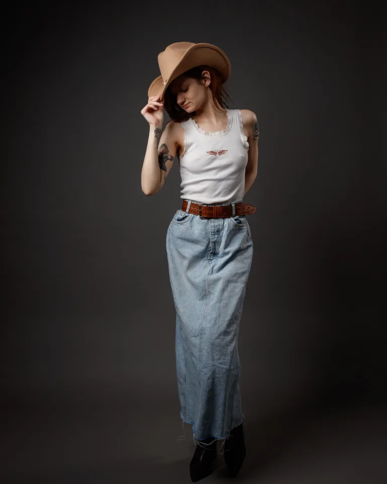 Woman in cowboy hat, white tank top, denim skirt