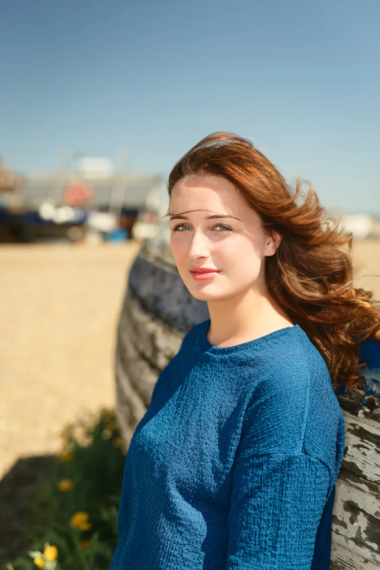 Red-haired woman in blue jumper at beach wall