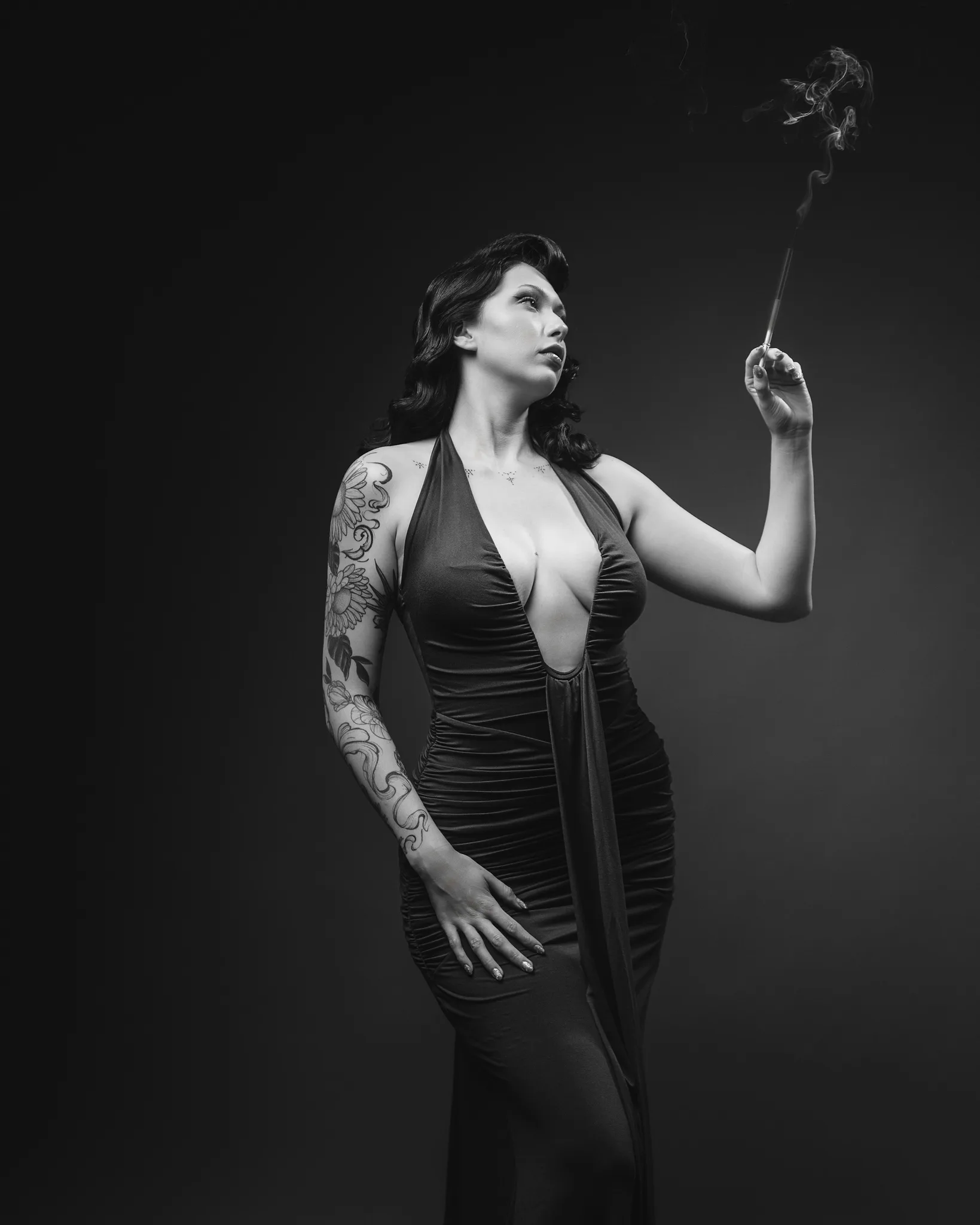 Woman with tattoos holding incense stick, black and white portrait