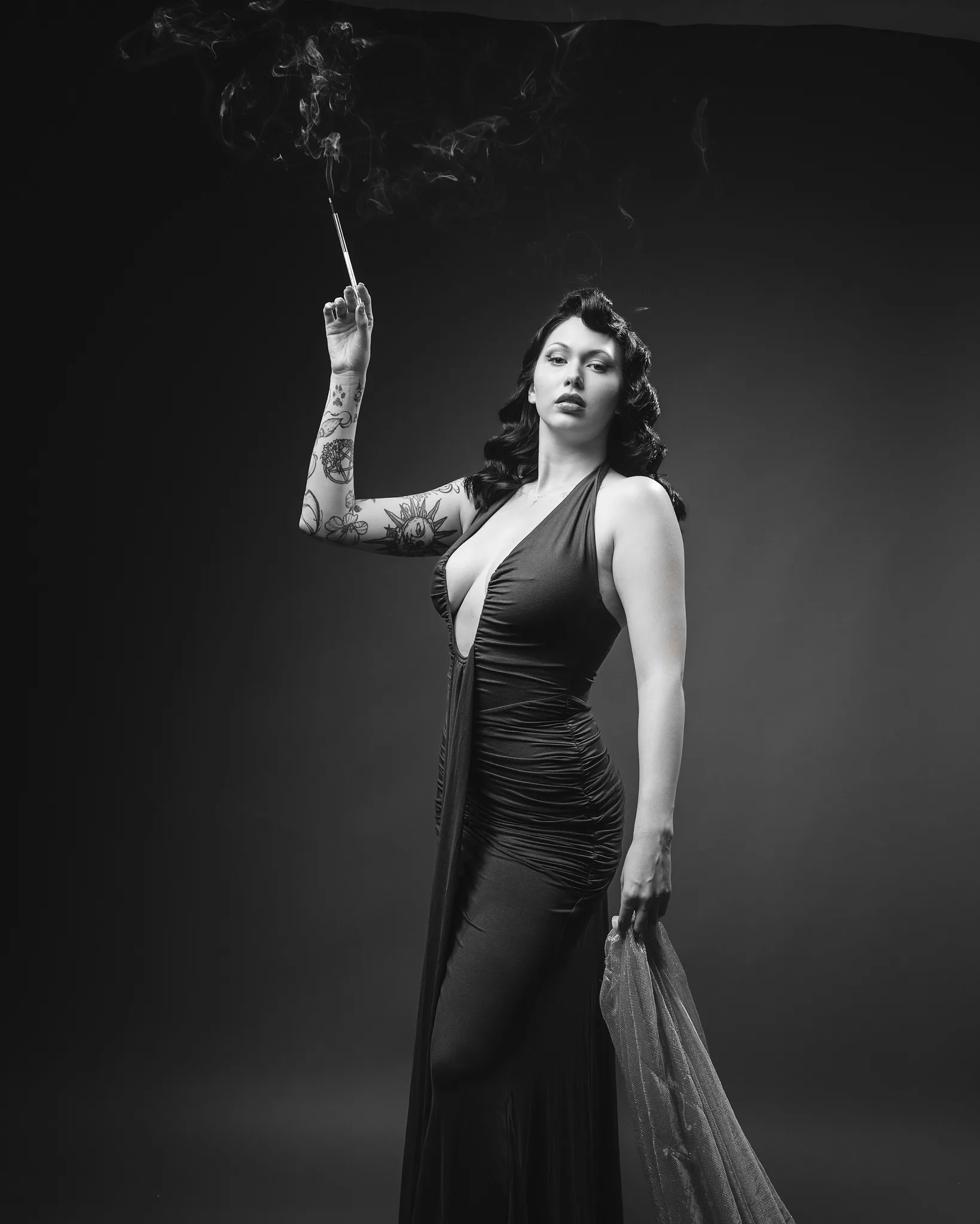 Tattooed woman in black dress holding cigarette holder