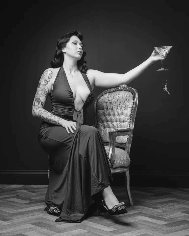 Tattooed woman in elegant dress holding martini glass