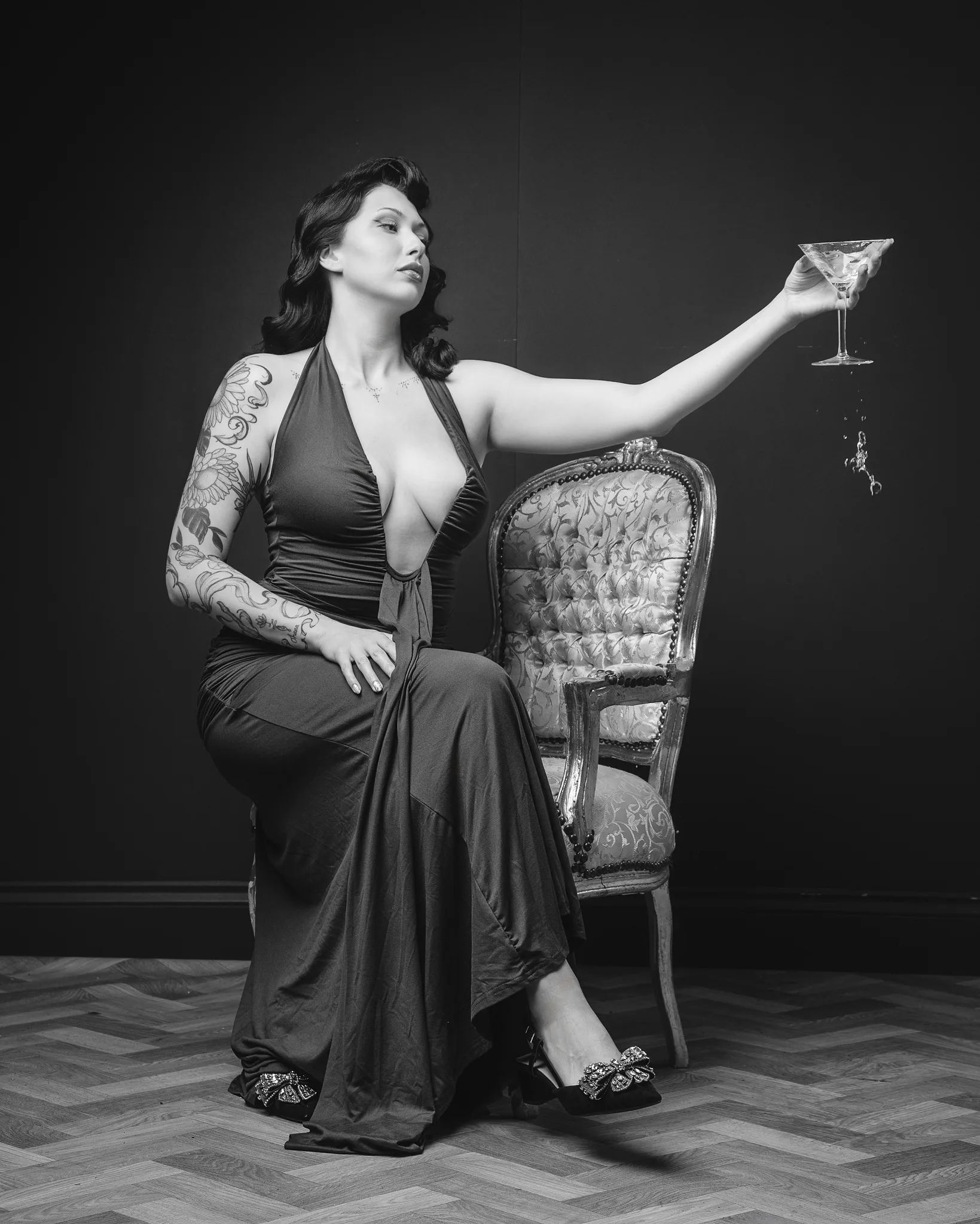 Tattooed woman in elegant dress holding martini glass