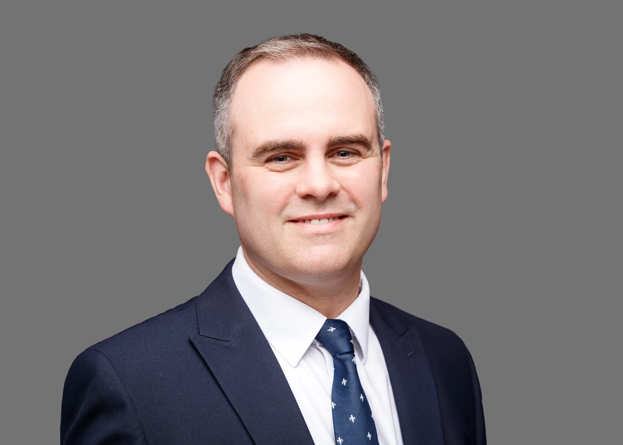 Professional headshot of man in navy suit and tie