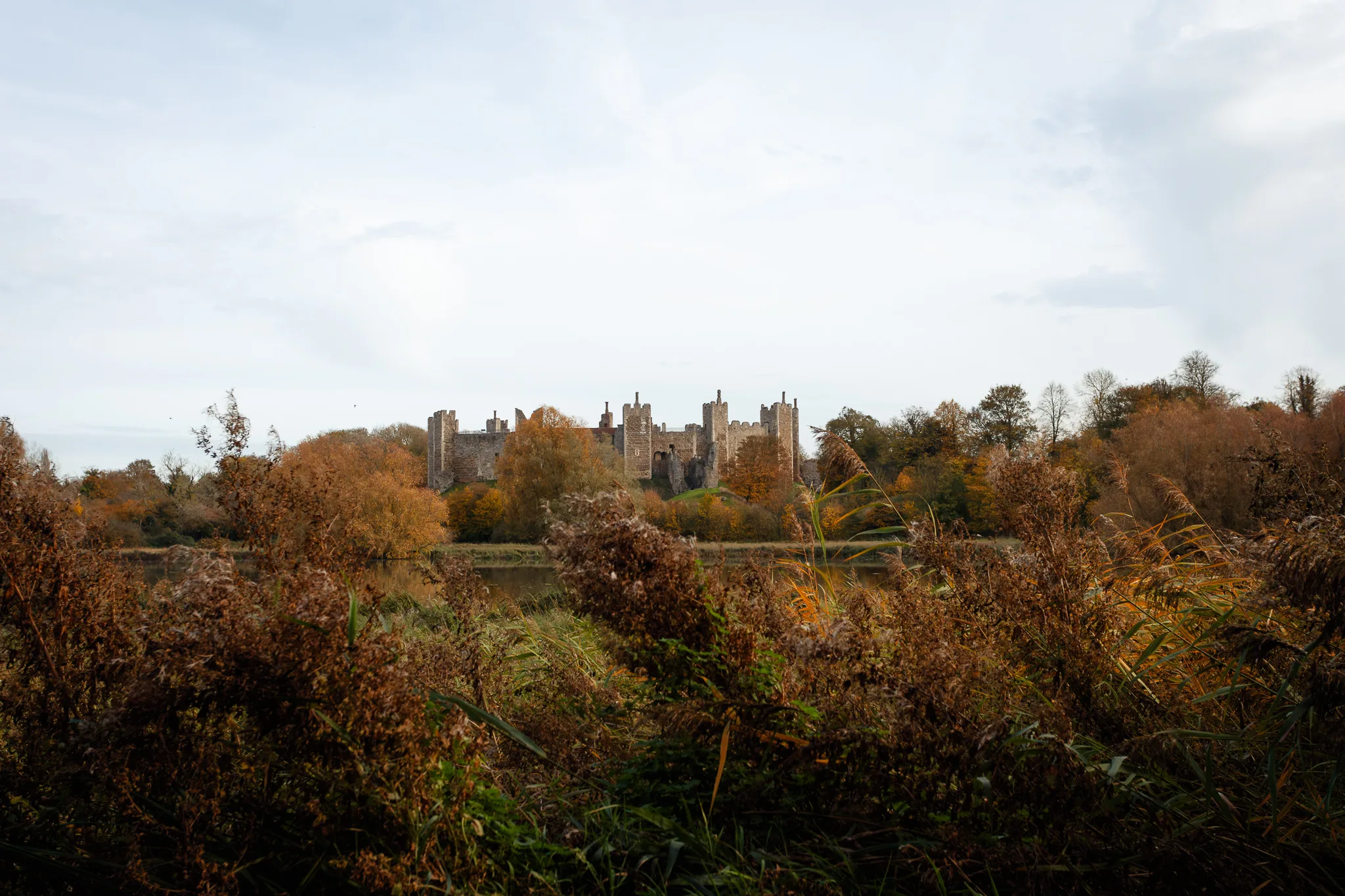Medieval castle across river with autumn woodland surroundings