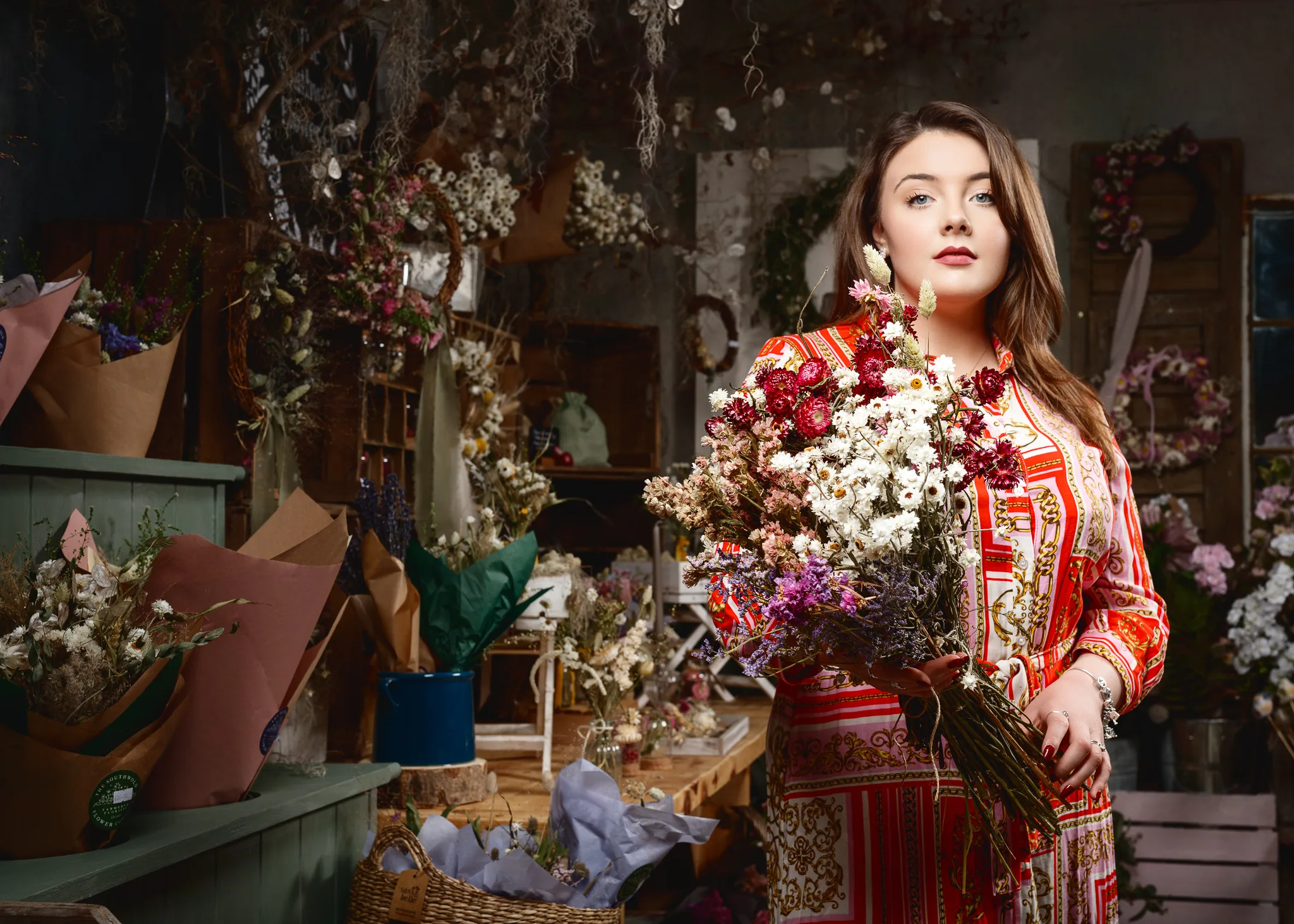 Woman in red ornate dress holding dried flower bouquet in florist shop