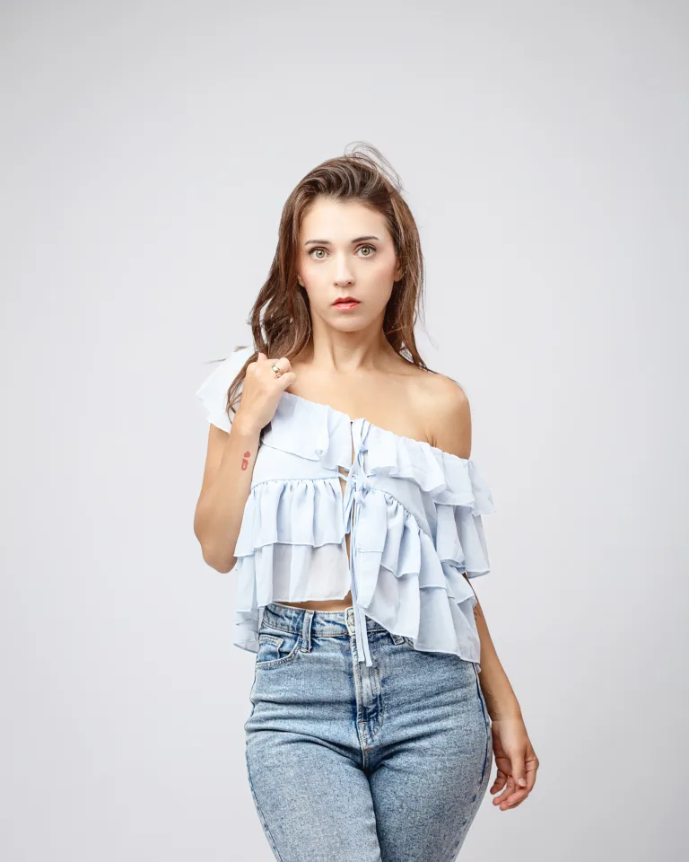 Woman wearing off-shoulder ruffled white top and jeans