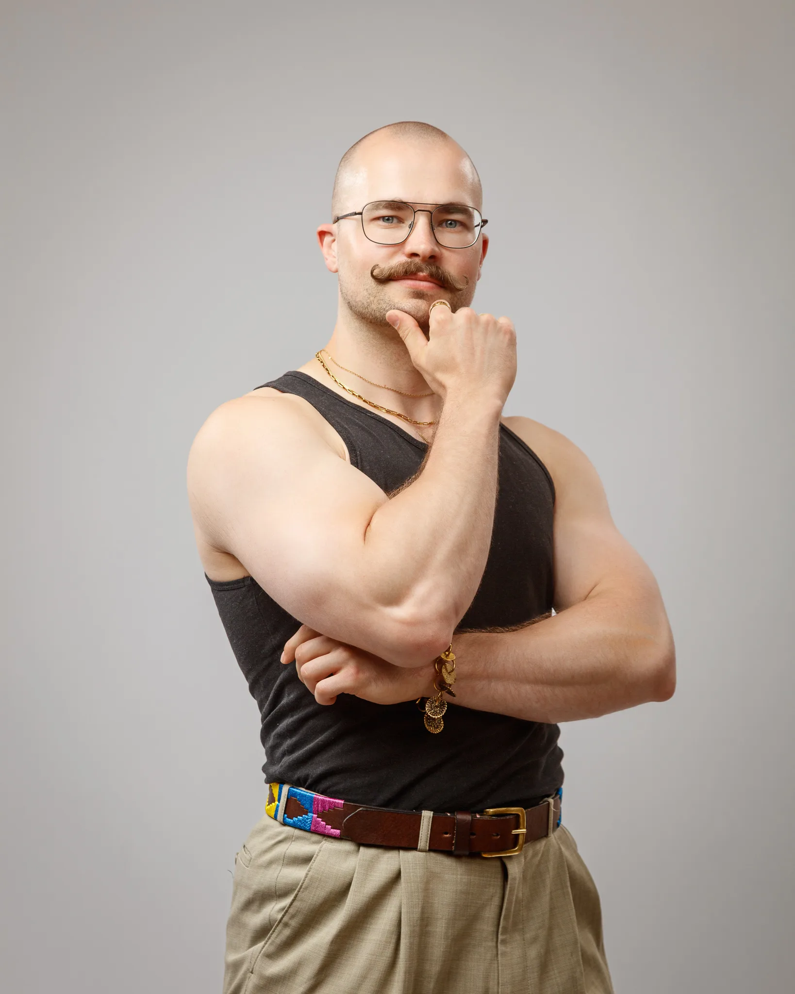 Bald man wearing glasses poses thoughtfully with hand to chin