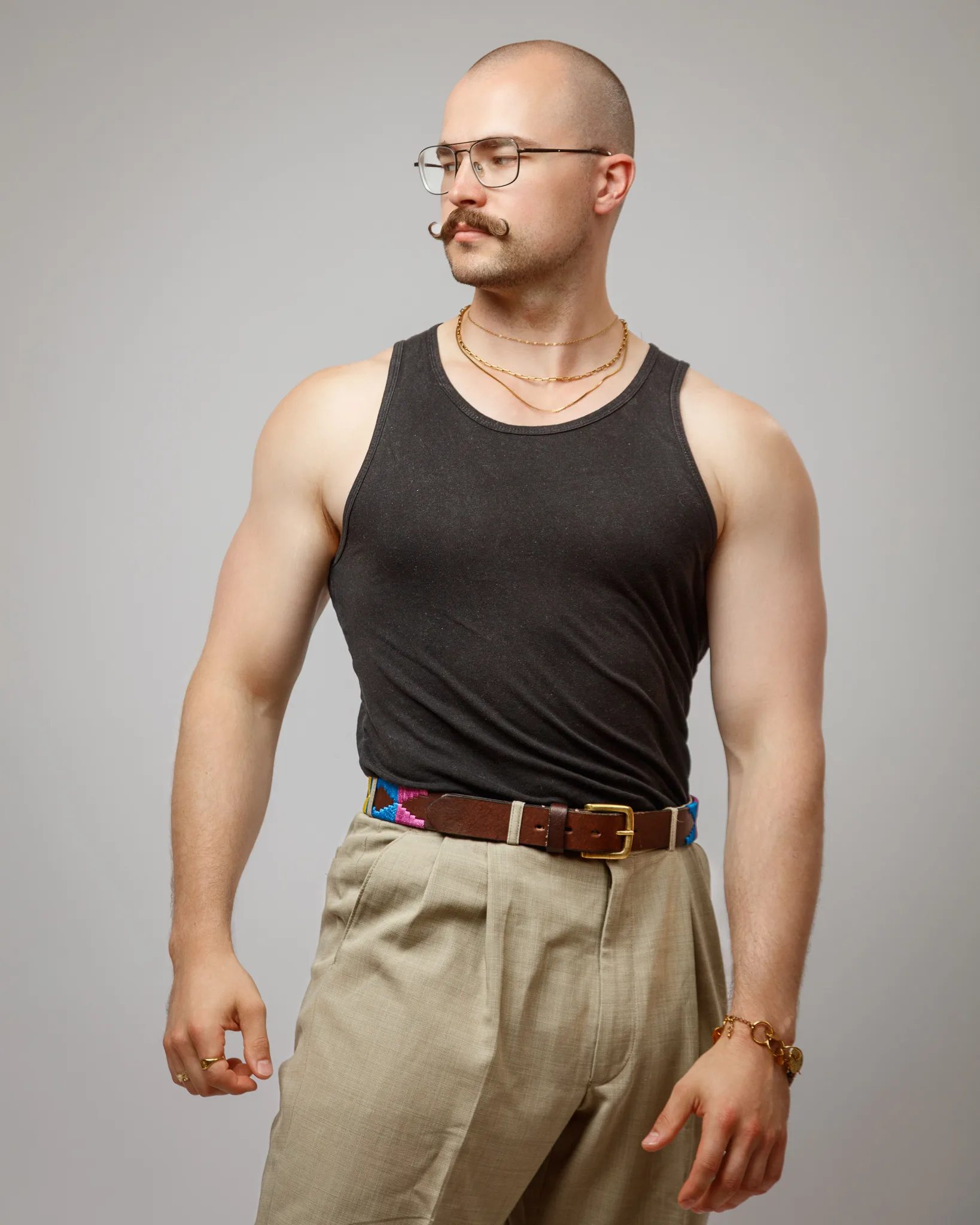Man wearing glasses, black tank top, and beige trousers