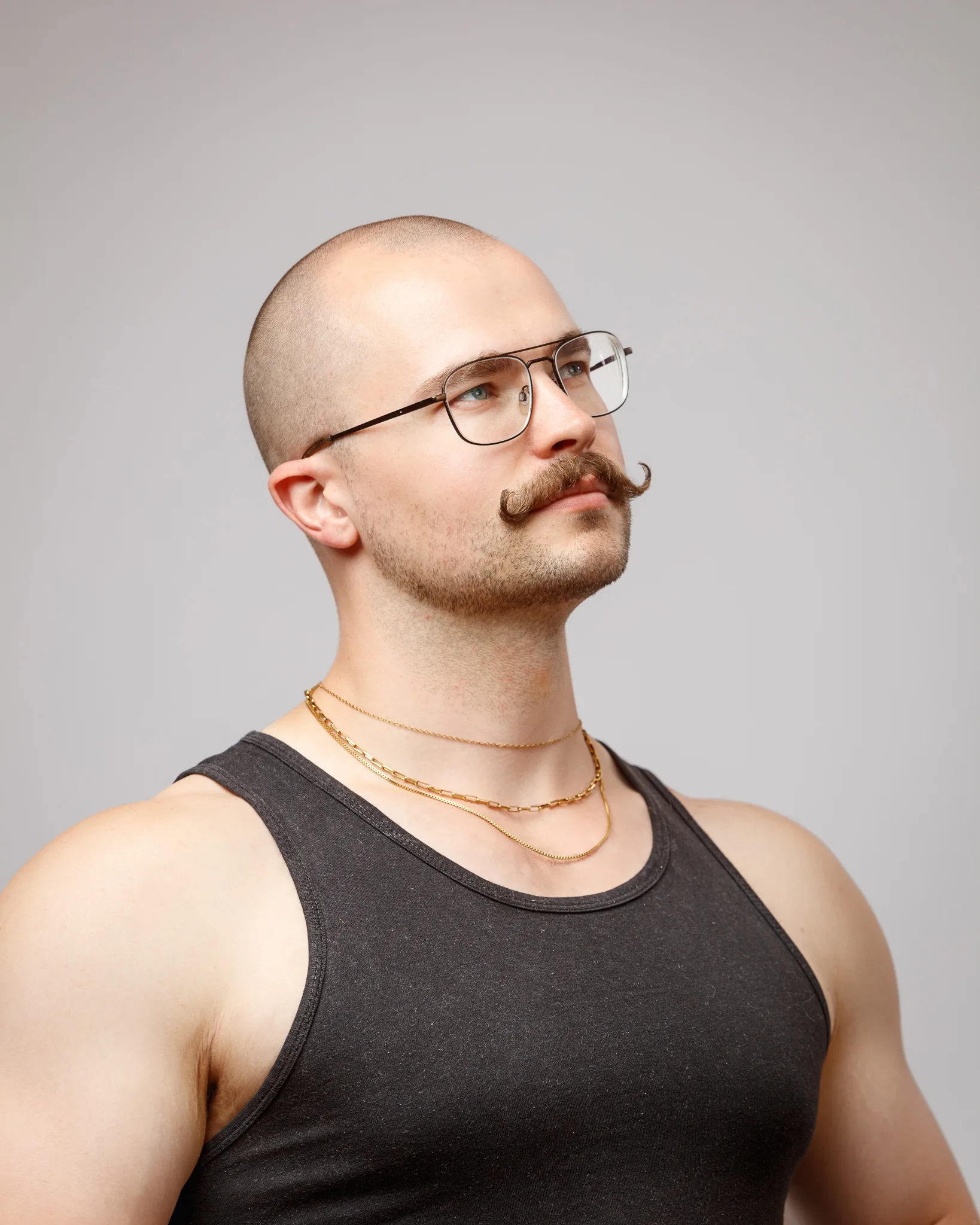 Man with glasses, beard, and gold chain necklace