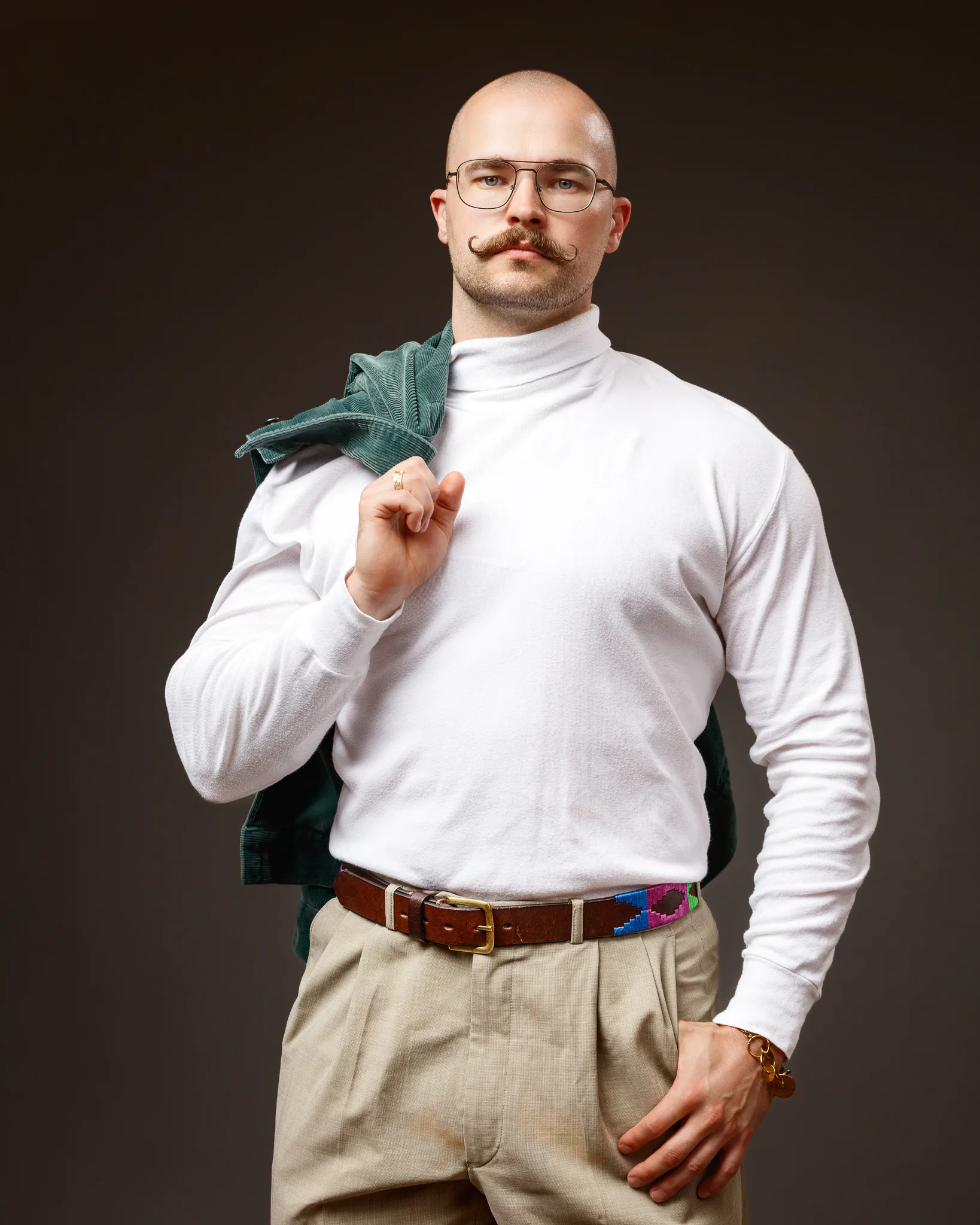 Bald man with glasses wearing white jumper and beige trousers
