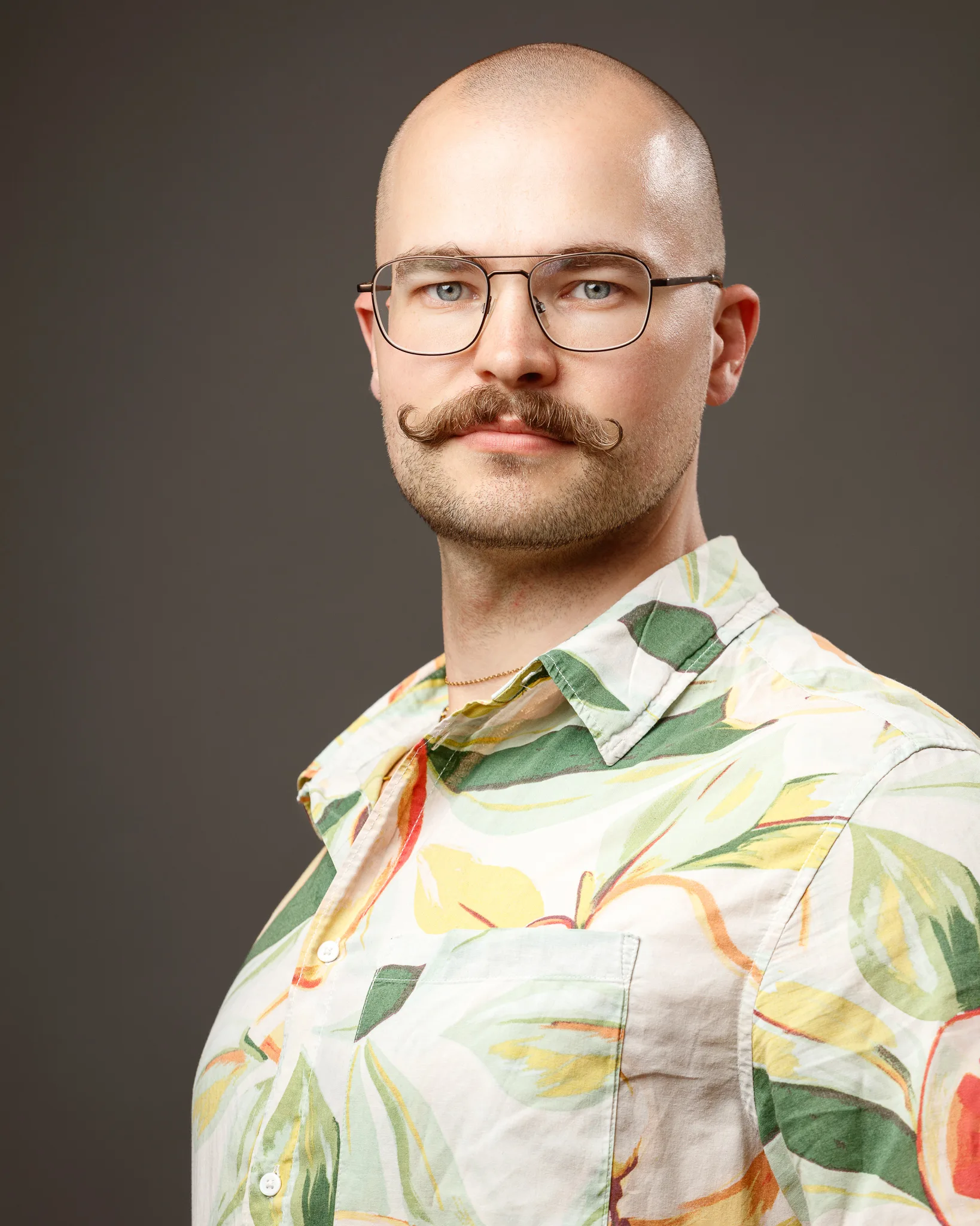 Man with glasses and moustache wearing patterned shirt