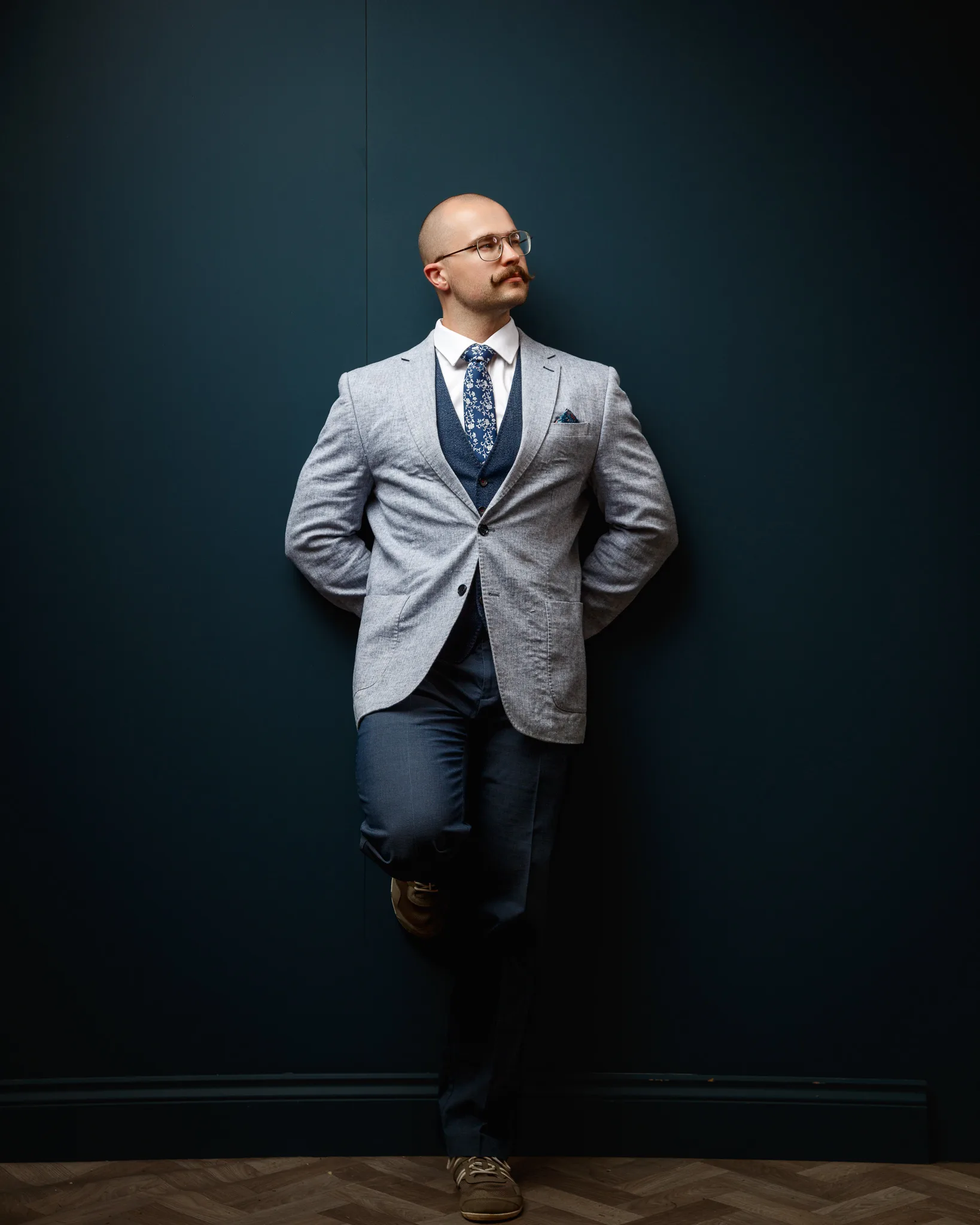 Professional man in grey blazer against dark teal background