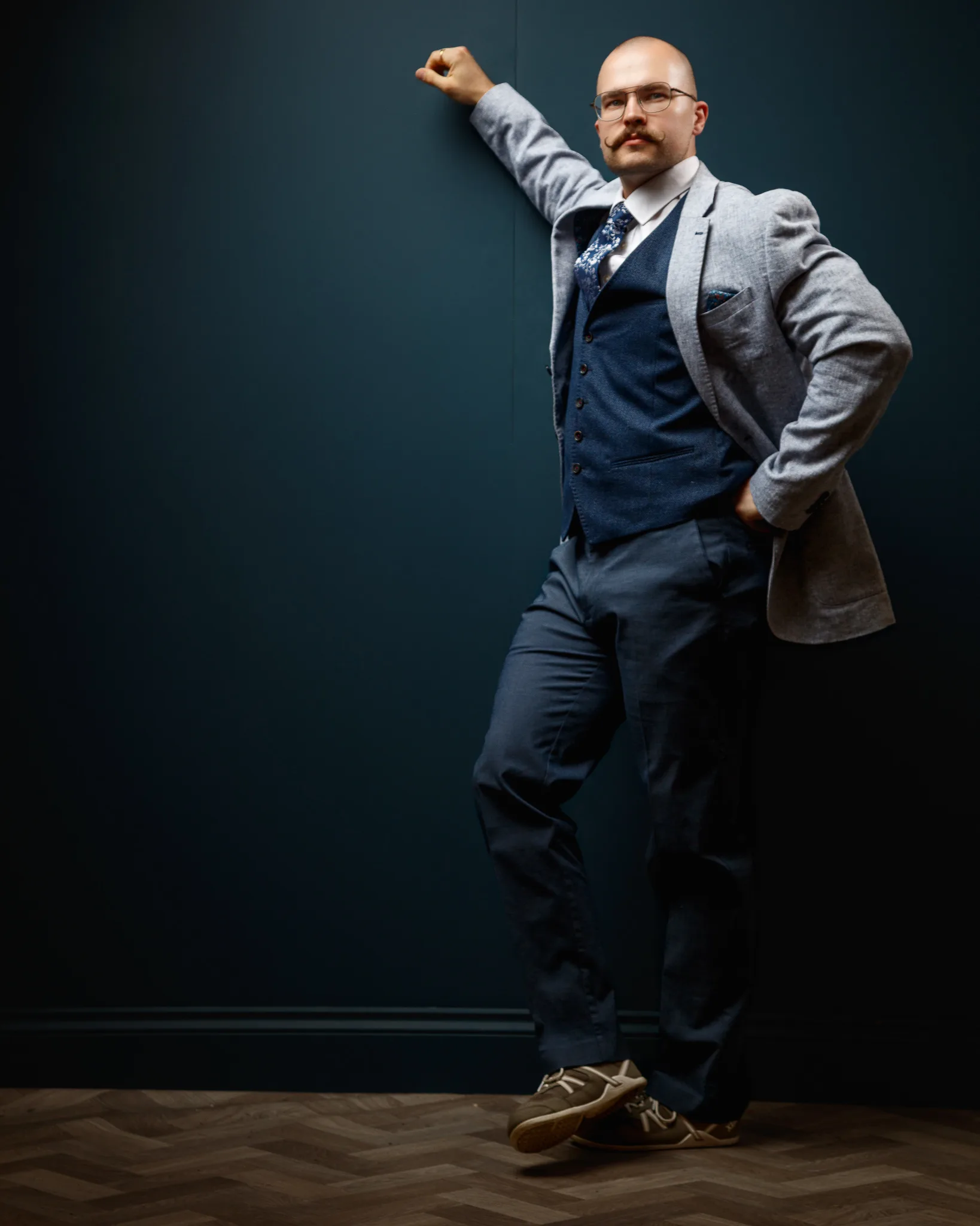 Confident businessman in grey blazer and glasses posing
