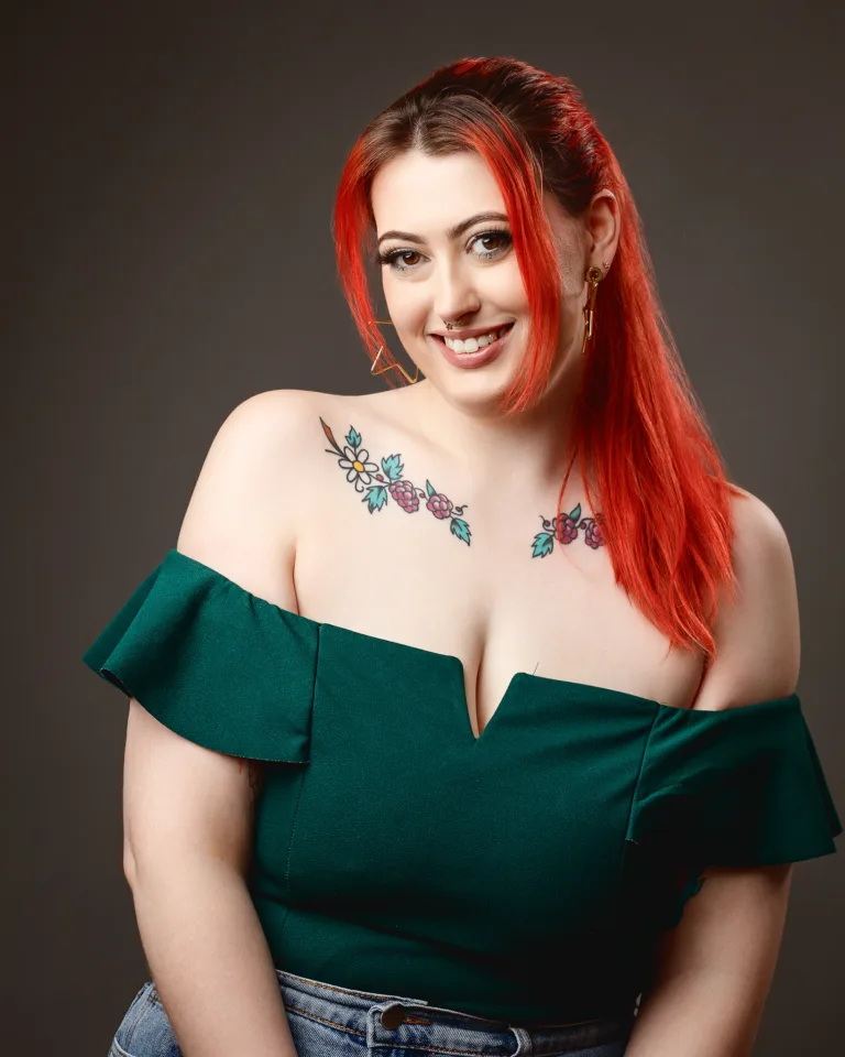Woman with red hair and floral shoulder tattoo smiling
