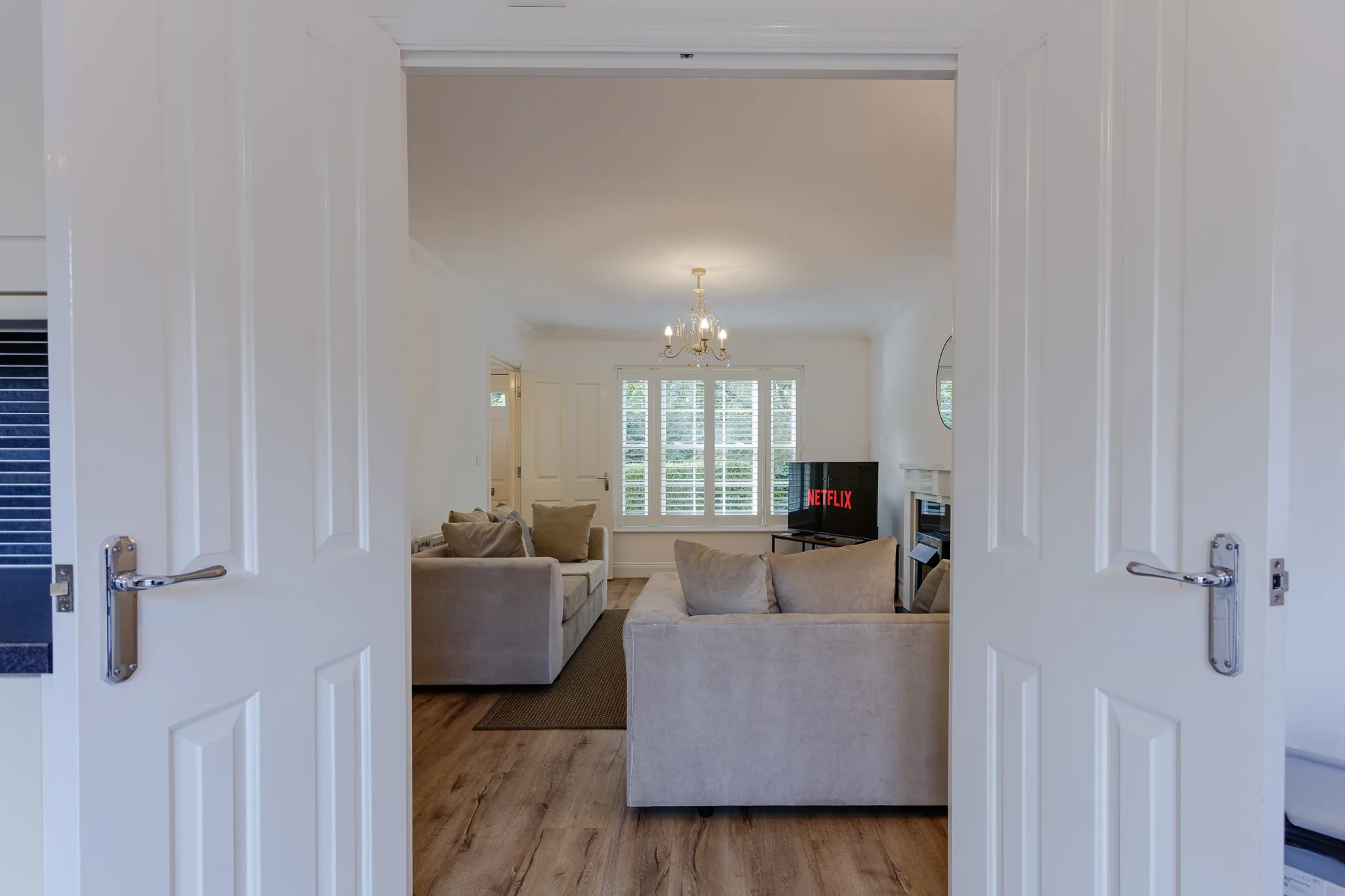 Modern living room viewed through open double doors with sofas
