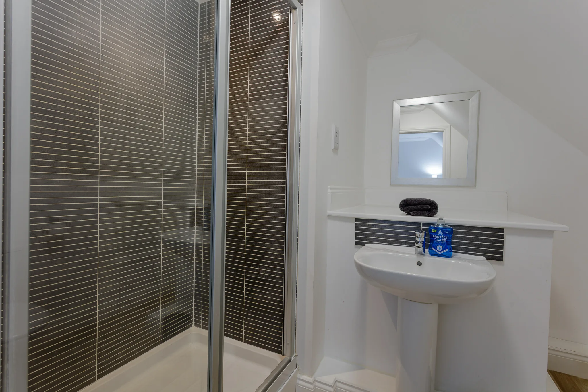 Modern bathroom with dark tile shower and white pedestal sink