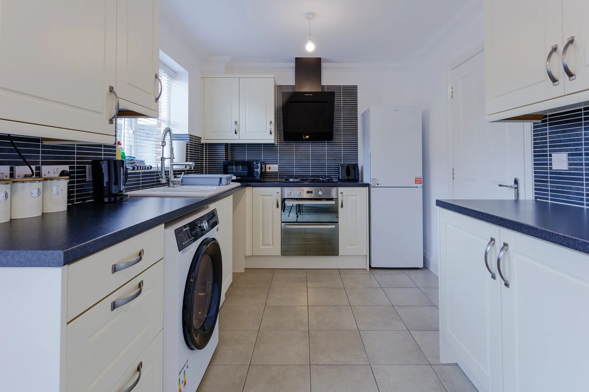 Modern kitchen with cream cabinets, dark blue countertops and tiles