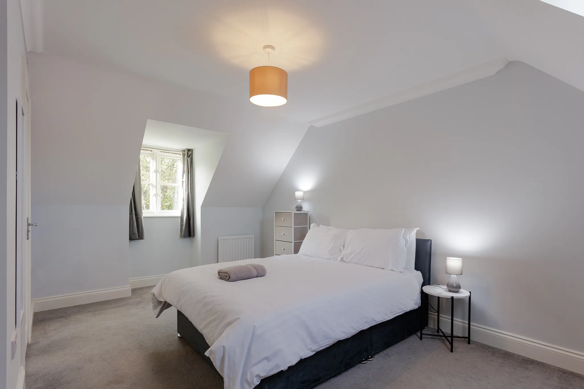 Bright modern attic bedroom with wooden pendant light