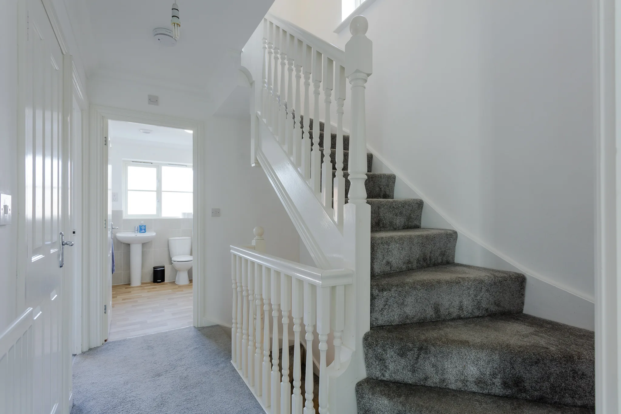 Modern hallway with white staircase and grey carpet stairs