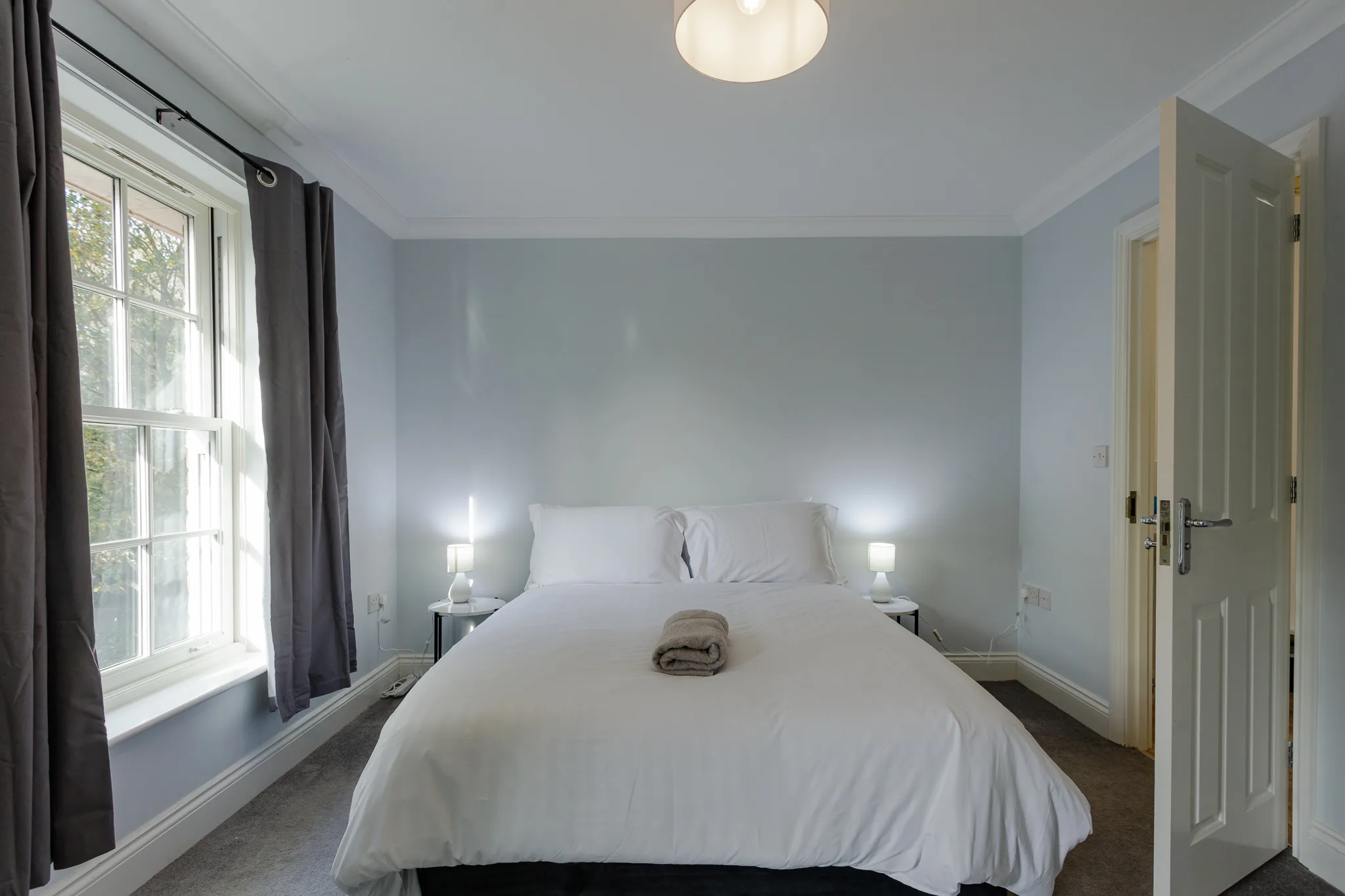 Modern bright bedroom with white bed and large window