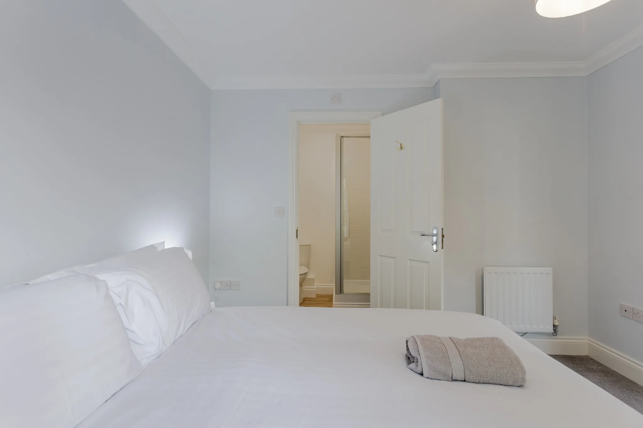 Minimalist white bedroom with ensuite bathroom and modern furnishings