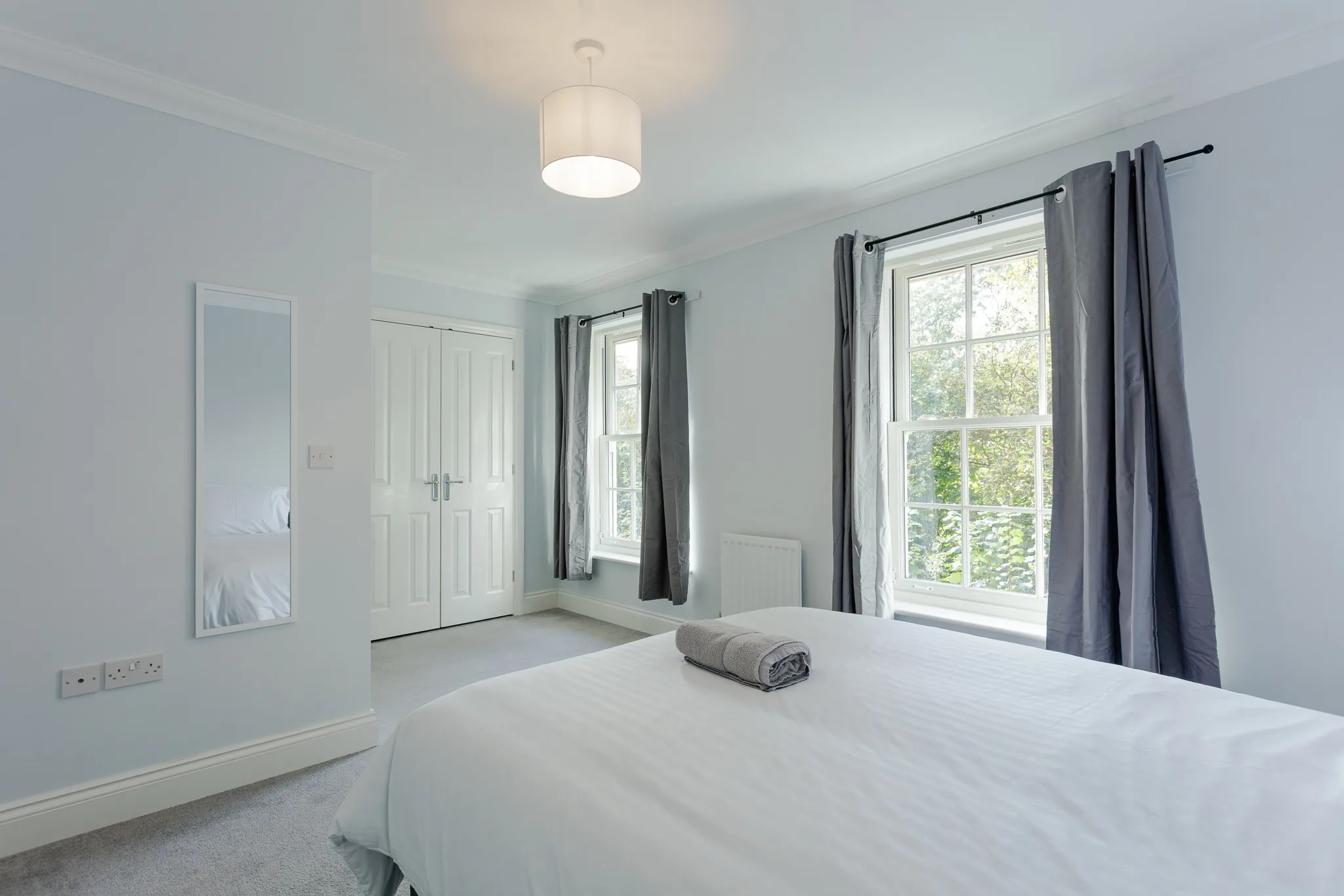 Modern white bedroom with double bed and large windows