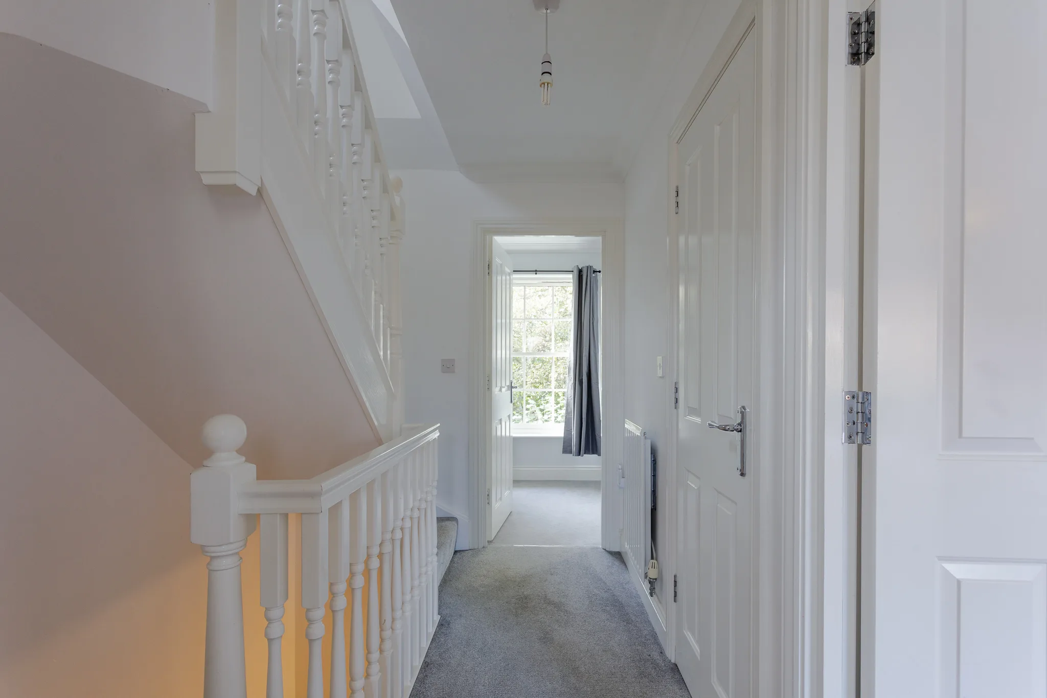 Bright white hallway with staircase and natural light