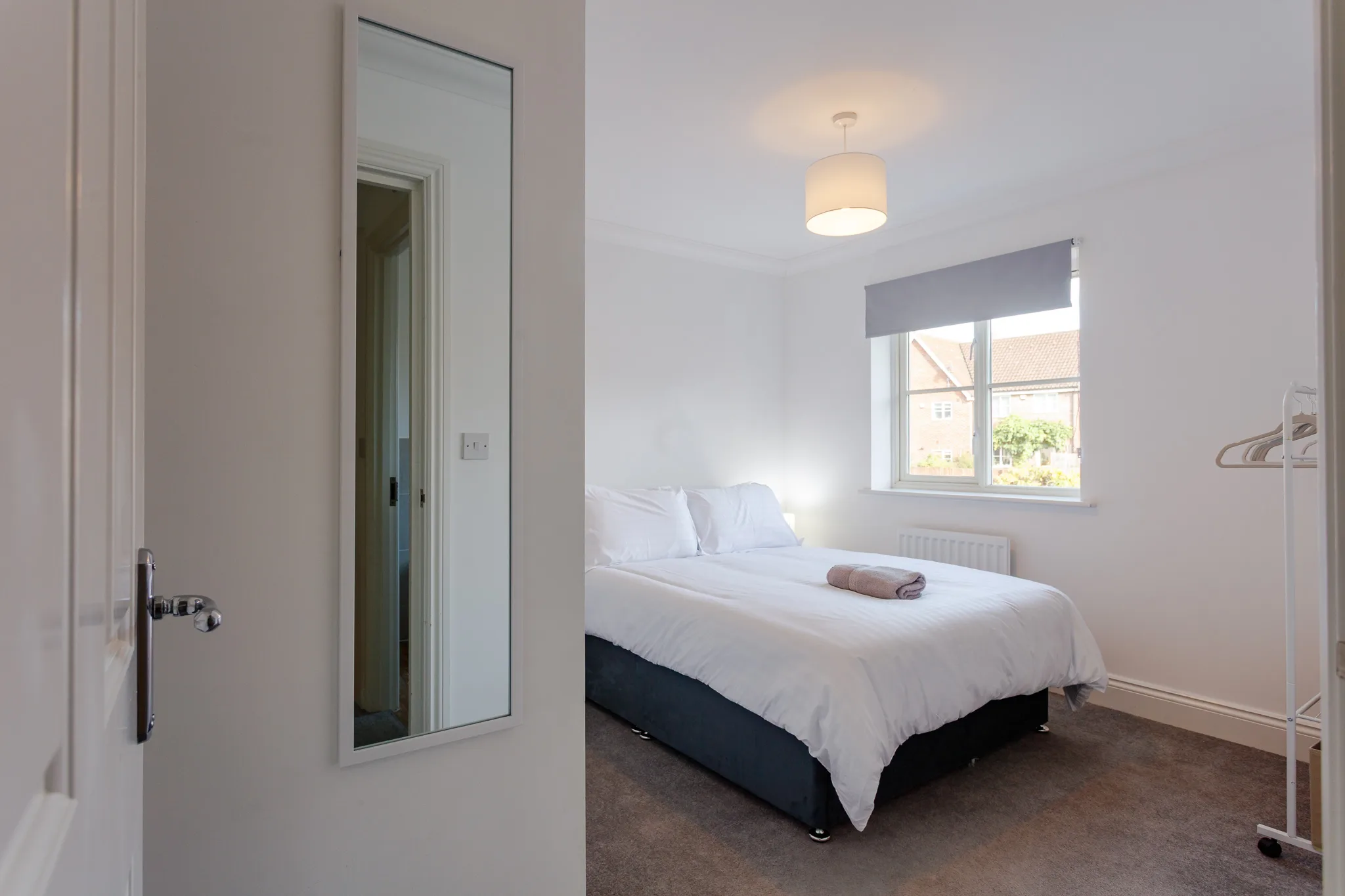 Modern bright bedroom with double bed and large mirror